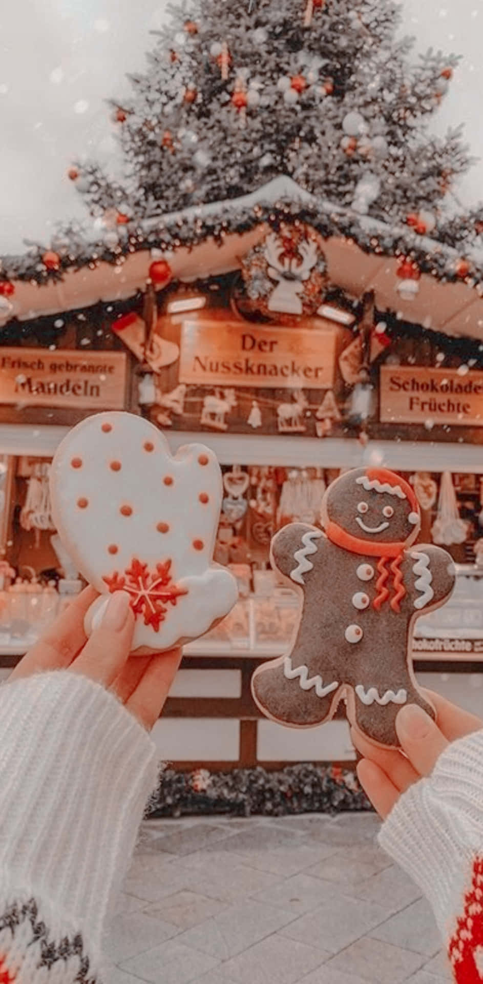 Tumblr Christmas 桌布 壁紙 — 雙手在白雪皚皚的聖誕市集攤位前，拿著形狀像手套和男人的節日薑餅餅乾。
