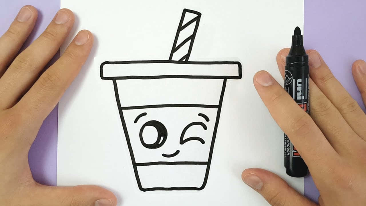 Boba Tea 桌布 壁紙 — 雙手拿著一張白紙，上面畫有一個可愛的卡通飲料杯，杯上有眨眼的表情和條紋吸管，用粗黑色馬克筆繪製。