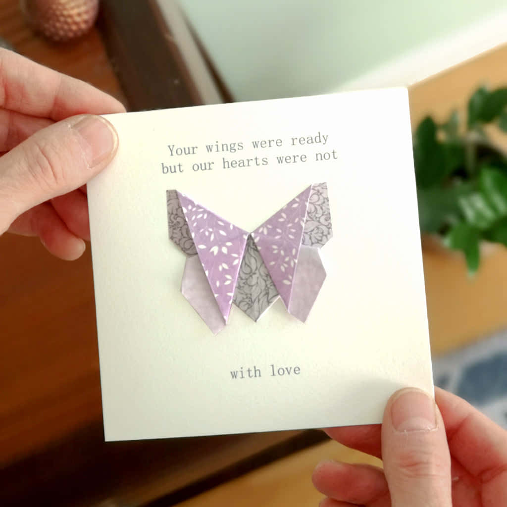 Butterfly Origami 桌布 壁紙 — 雙手拿著一張白色卡片，上面有紫色摺紙蝴蝶和關於心與翅膀的文字。