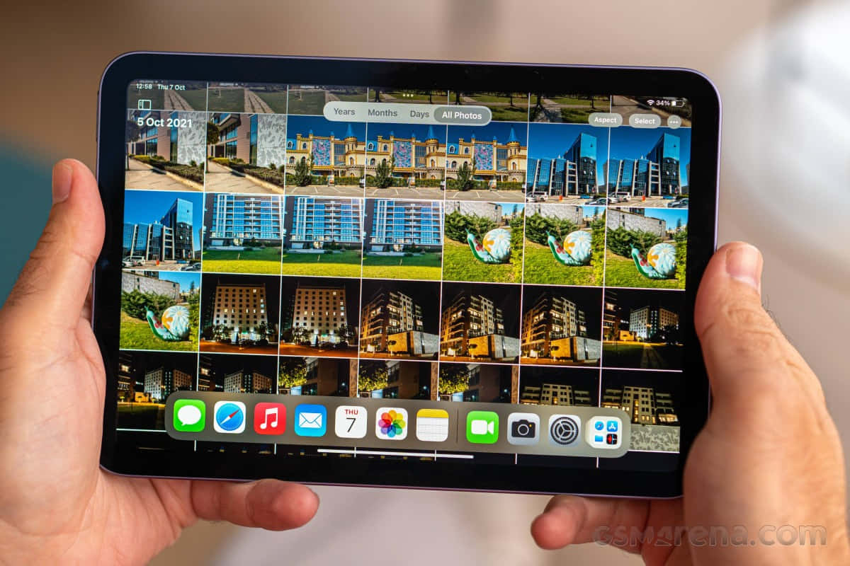 兩隻手拿著平板電腦，顯示建築物和雕塑的照片庫。 — iPad mini 動態圖片 壁紙