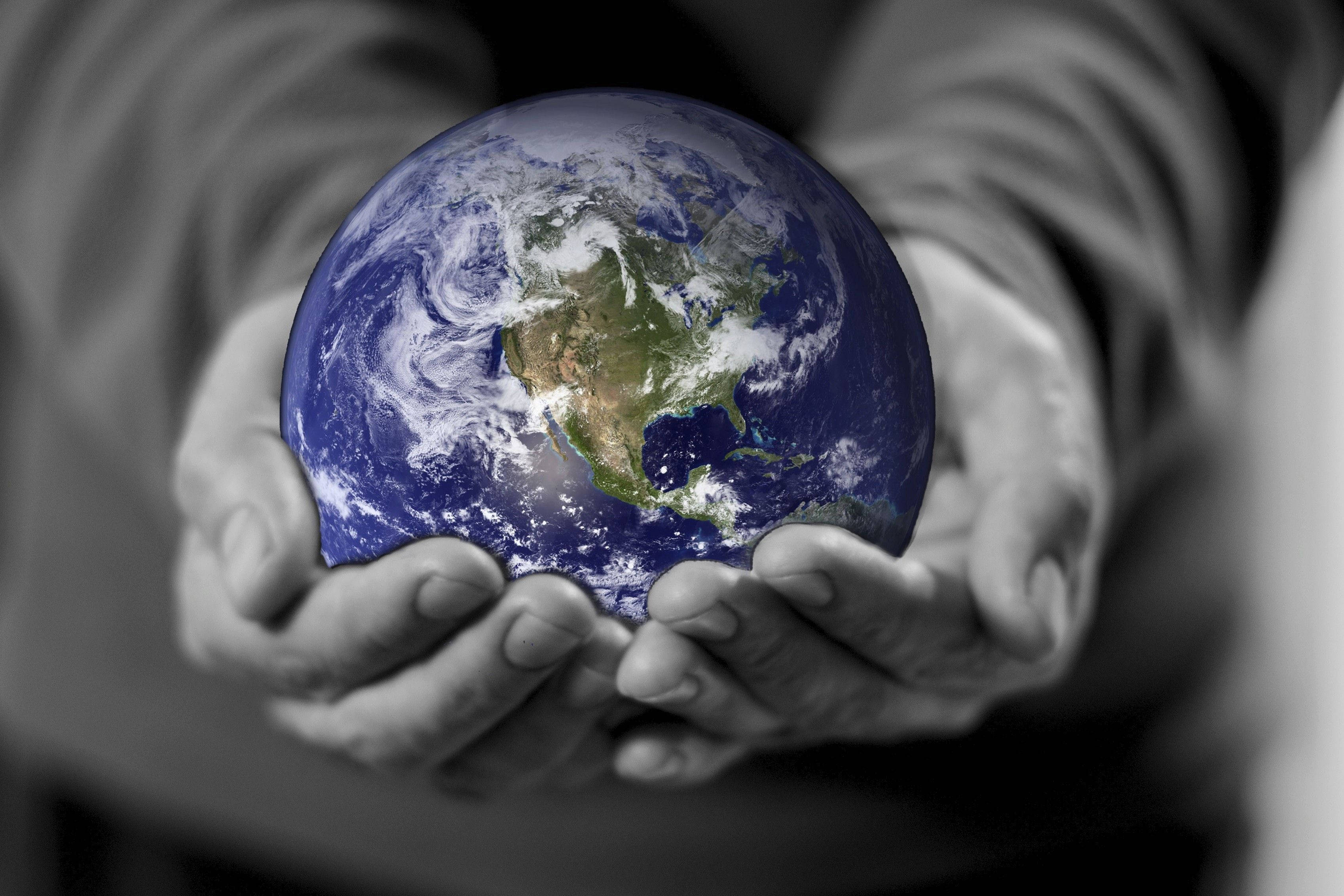 Earth Day 桌布 壁紙 — 雙手捧著一個色彩繽紛的地球儀，背景為單色調，強調全球關懷和環境責任。