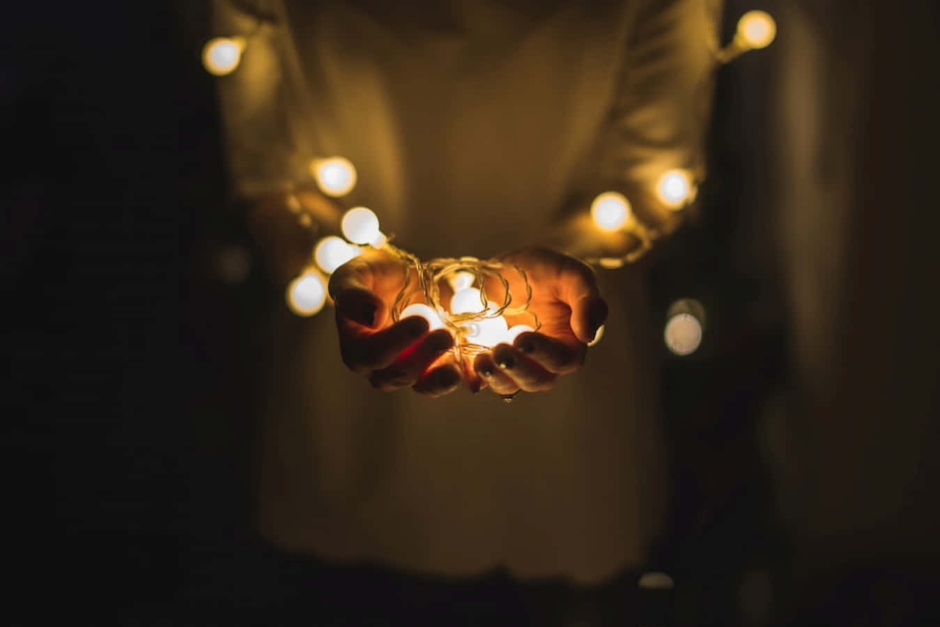 Light 桌布 壁紙 — 雙手捧著發光的仙女燈，在黑暗背景下營造溫馨親密的氛圍。