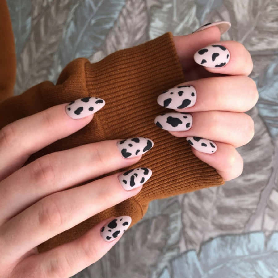 Nail 桌布 壁紙 — 雙手特寫，帶有乳牛紋指甲，擱在棕色羅紋袖子上，背景為有紋理的灰色布料。