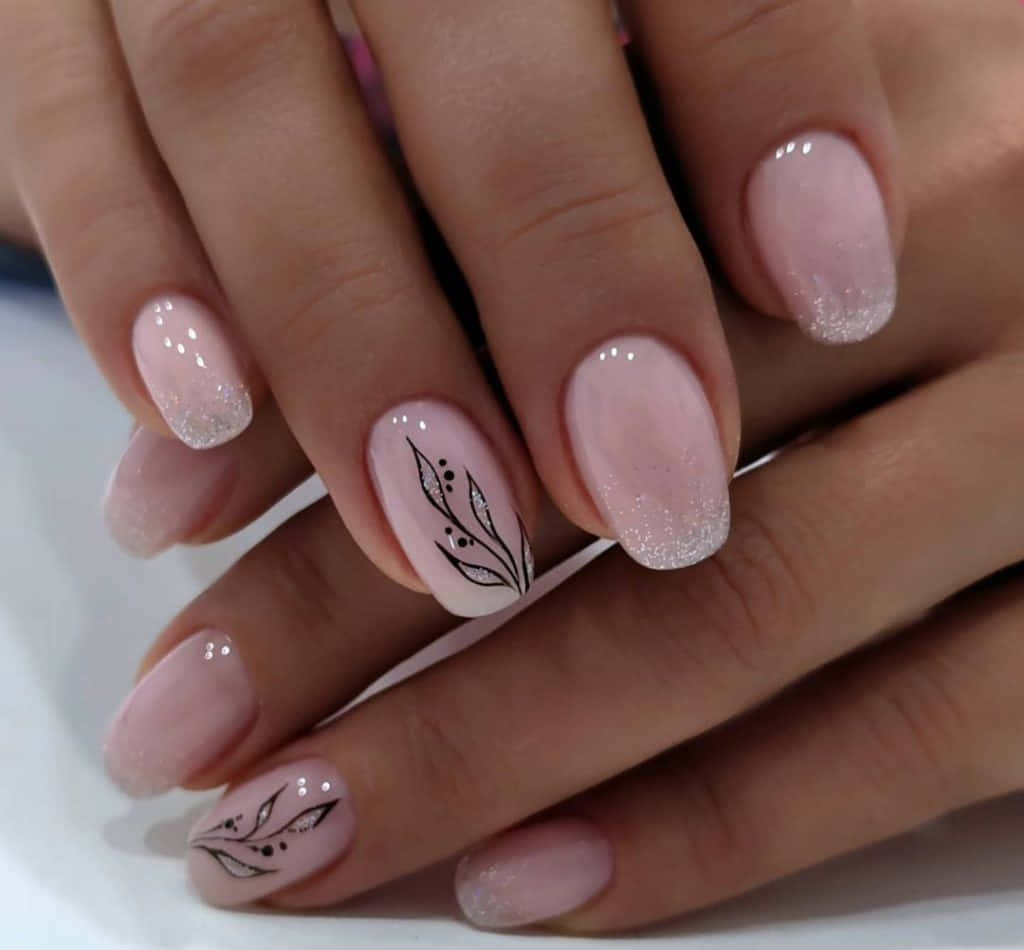 Pink Nail Art 桌布 壁紙 — 雙手特寫，帶有柔和粉紅閃粉指甲，兩隻手指上有精緻的黑色葉子圖案。