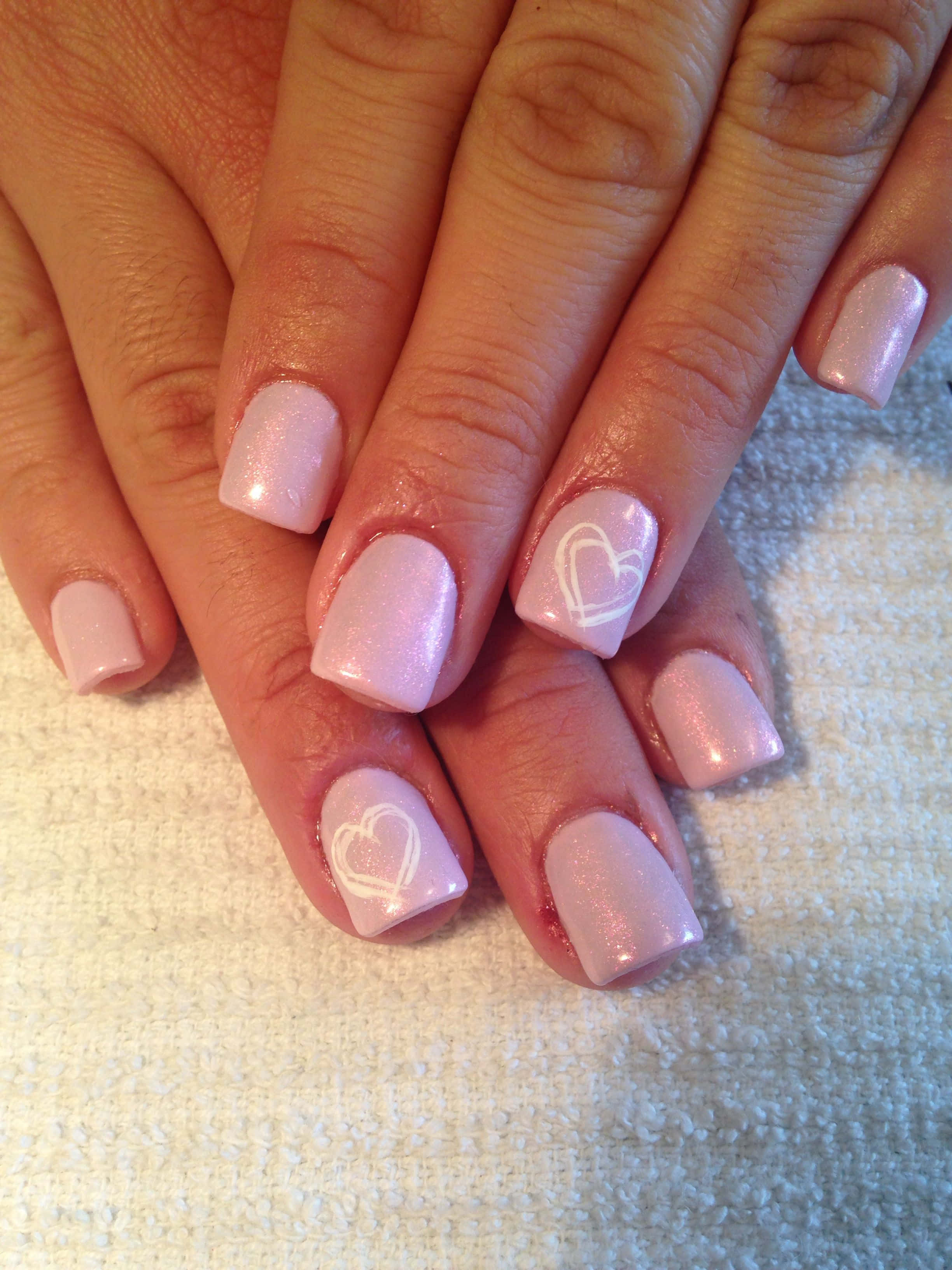 Pink Nail Art 桌布 壁紙 — 雙手特寫，帶有淺粉紅色亮粉指甲和白色心形貼紙，放在有紋理的白色毛巾上。