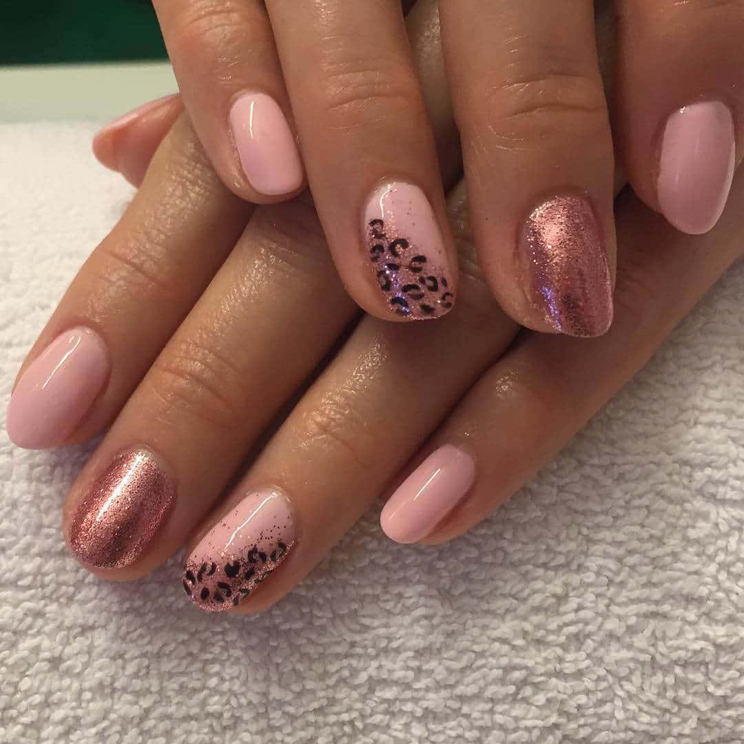 Pink Nail Art 桌布 壁紙 — 雙手特寫，帶有粉紅閃粉和豹紋指甲，放在白色毛巾上。