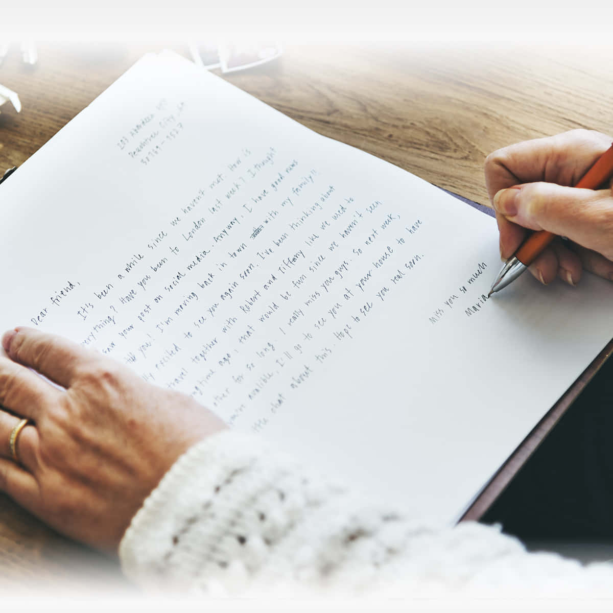 Letter 桌布 壁紙 — 雙手用紅色筆在木桌上的間線紙上寫一封真摯的信的特寫。