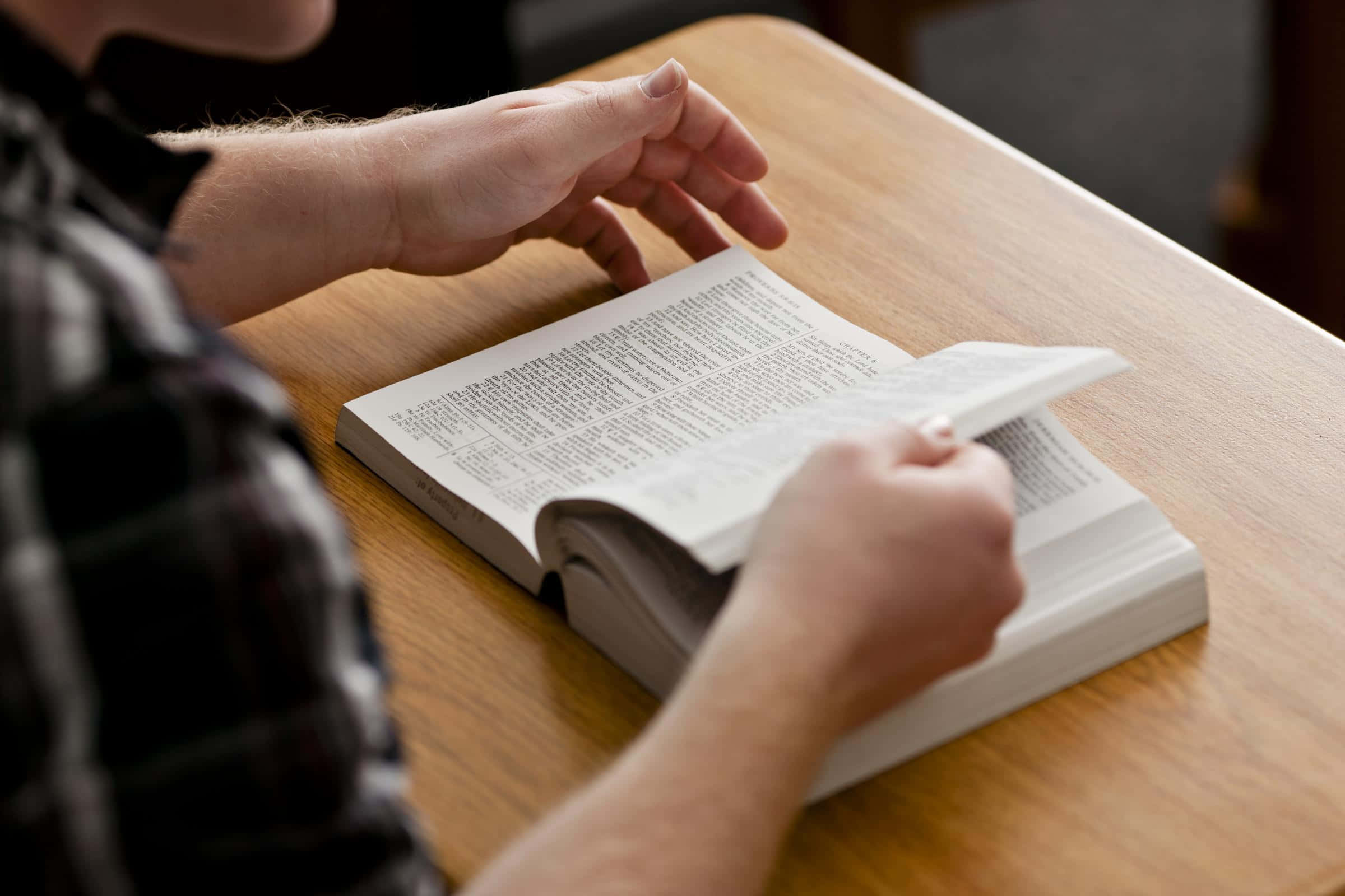 Studying 桌布 壁紙 — 雙手翻開放在木桌上的書本頁面的特寫。