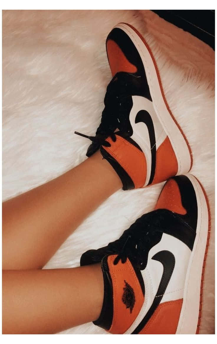 Cute Shoes 桌布 壁紙 — 雙腳穿著大膽的橙、黑、白色運動鞋，擱在毛絨白色地毯上的特寫。