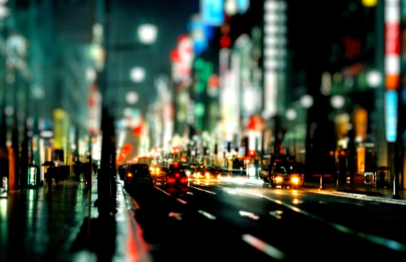 夜景城市 桌布 壁紙 — 雨夜中濕漉漉的城市街道，模糊的霓虹燈和流動的車頭燈營造出夢幻般的都市光芒。