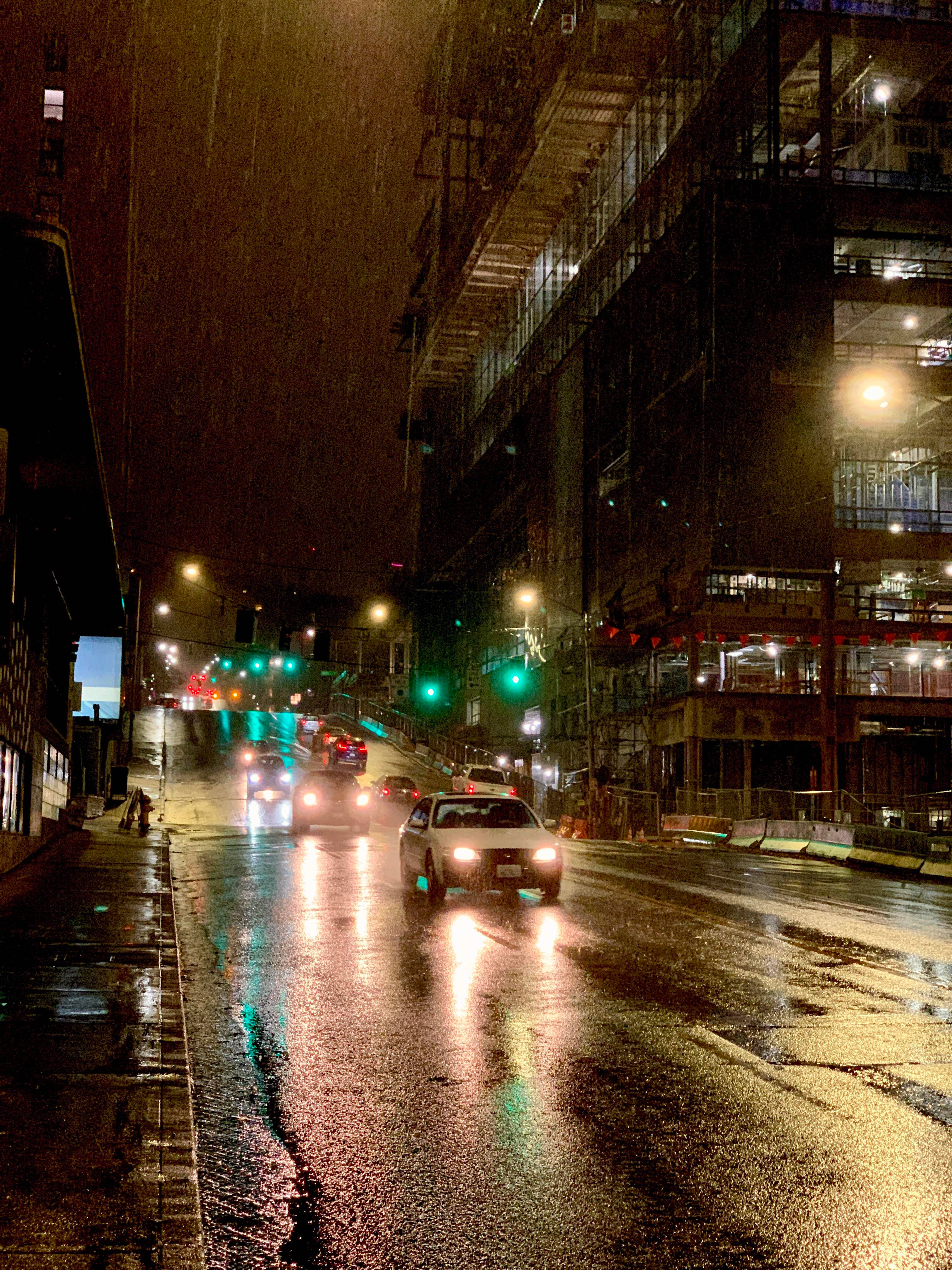 Rainy Day 桌布 壁紙 — 雨夜中濕漉漉的城市街道，車頭燈在街燈下的濕漉漉路面上閃爍反射。