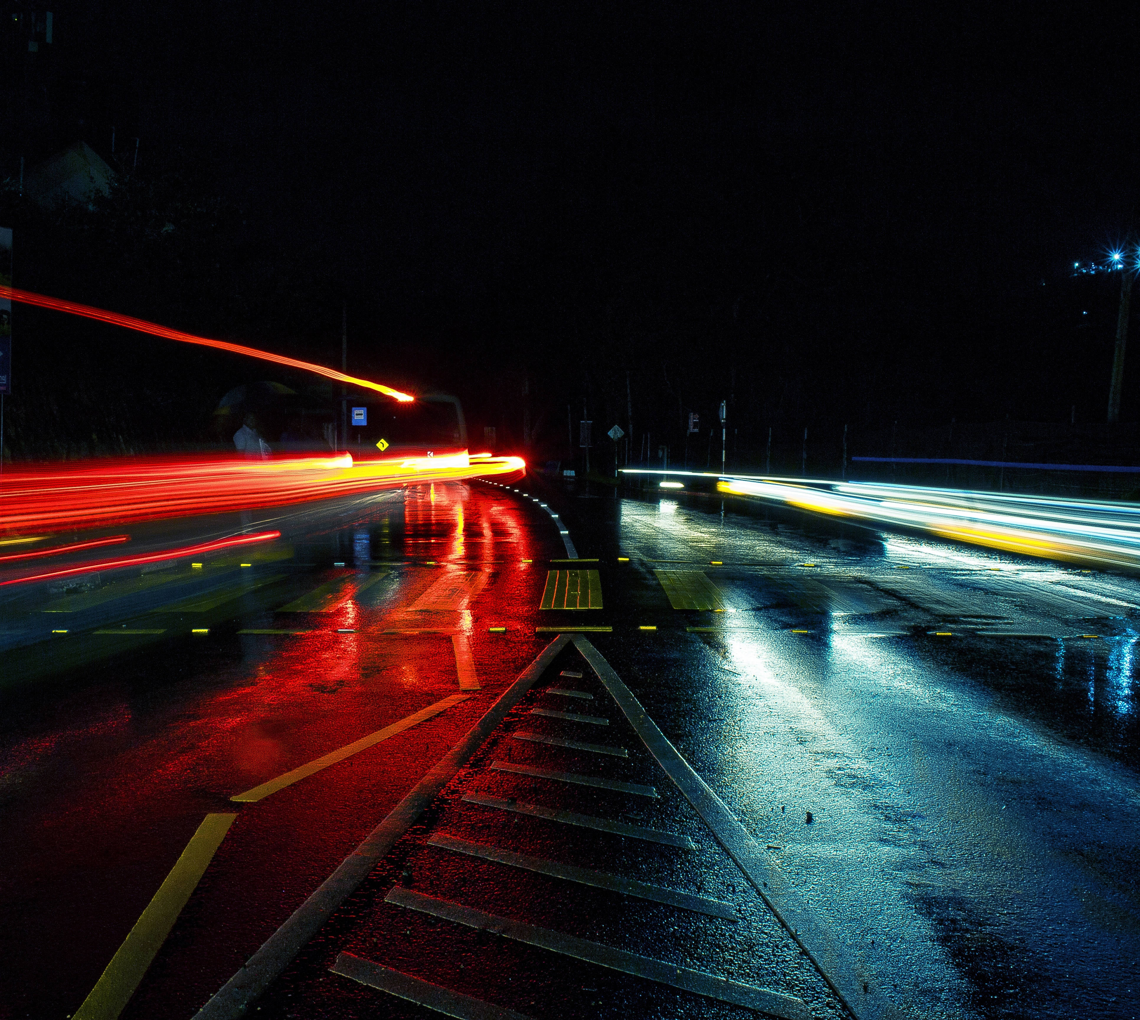 Street 桌布 壁紙 — 雨夜濕滑的道路上，有來往車輛留下的鮮豔紅色和白色光軌。