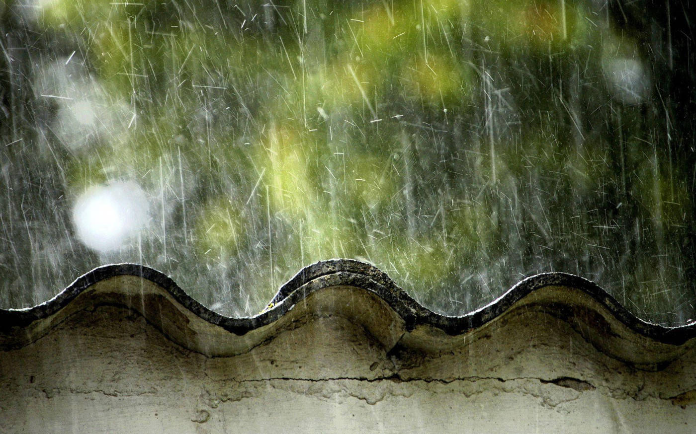 Rooftop 桌布 壁紙 — 雨水沿著飽經風霜的波紋鐵皮屋頂流下，背景是模糊的綠色。