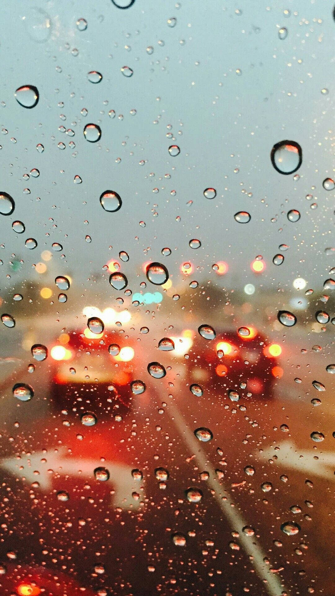 Rainy Day 桌布 壁紙 — 雨滴依附在汽車窗戶上，模糊的城市燈光溫暖地透過濕玻璃閃爍。