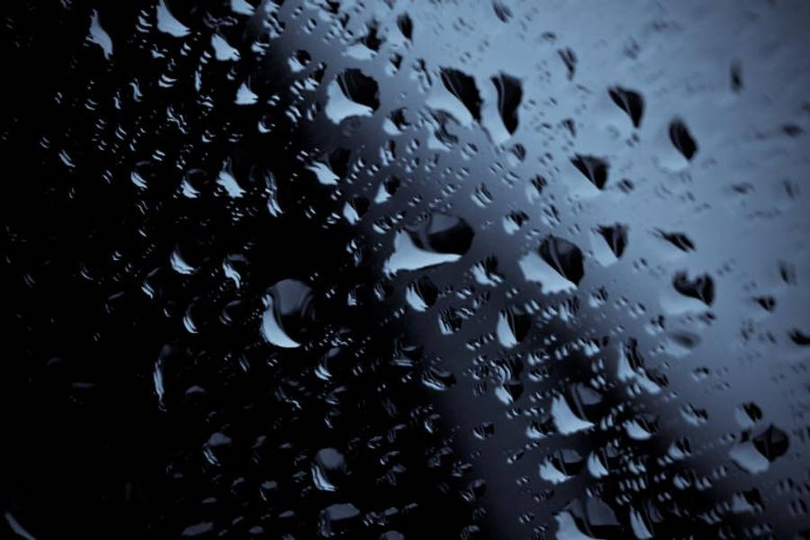 Droplets 桌布 壁紙 — 雨滴依附在深色玻璃表面，映照出陰鬱的藍灰色天空。