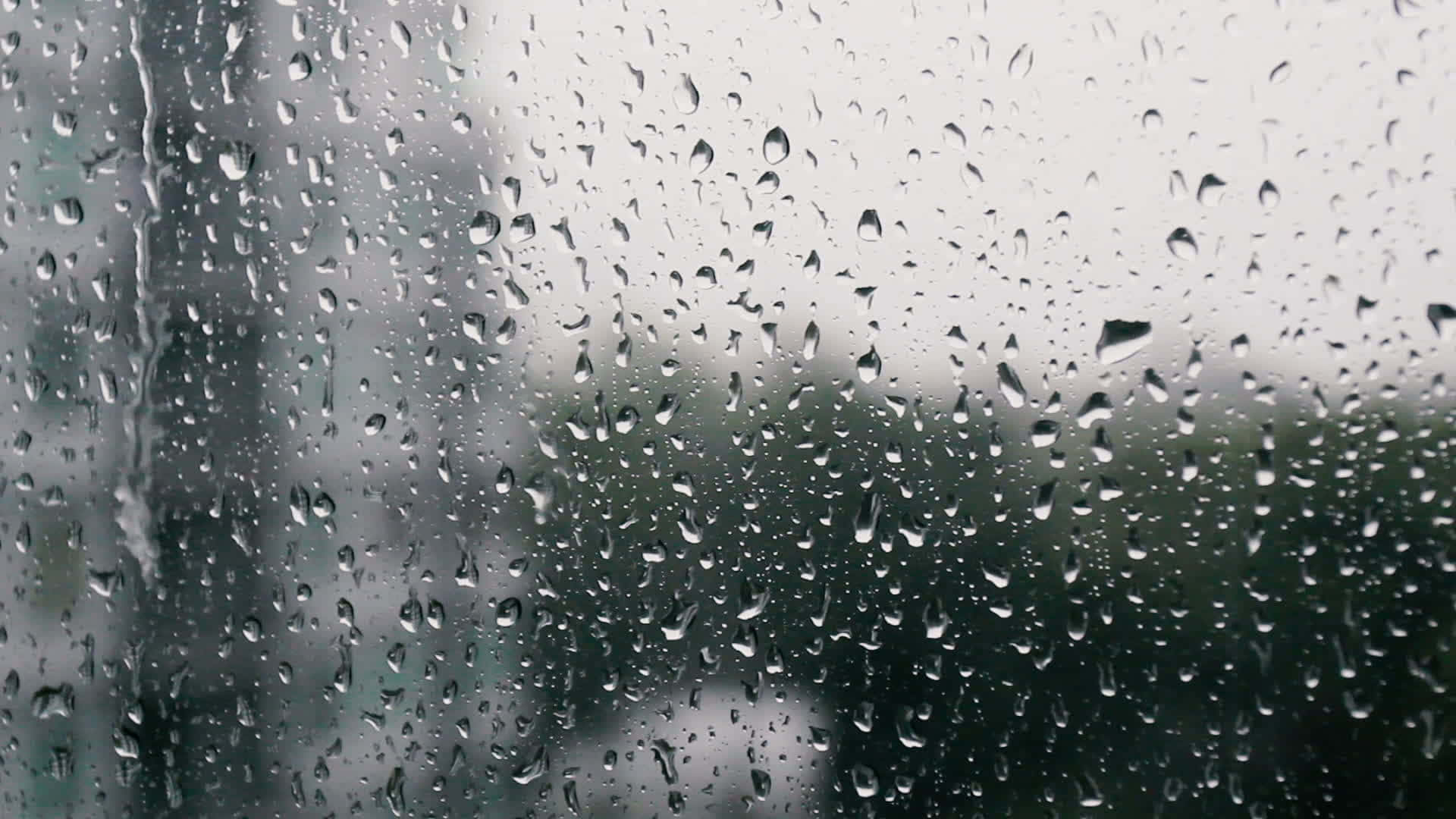下雨 桌布 壁紙 — 雨滴依附在玻璃窗上，模糊了外面灰色的城市景象。