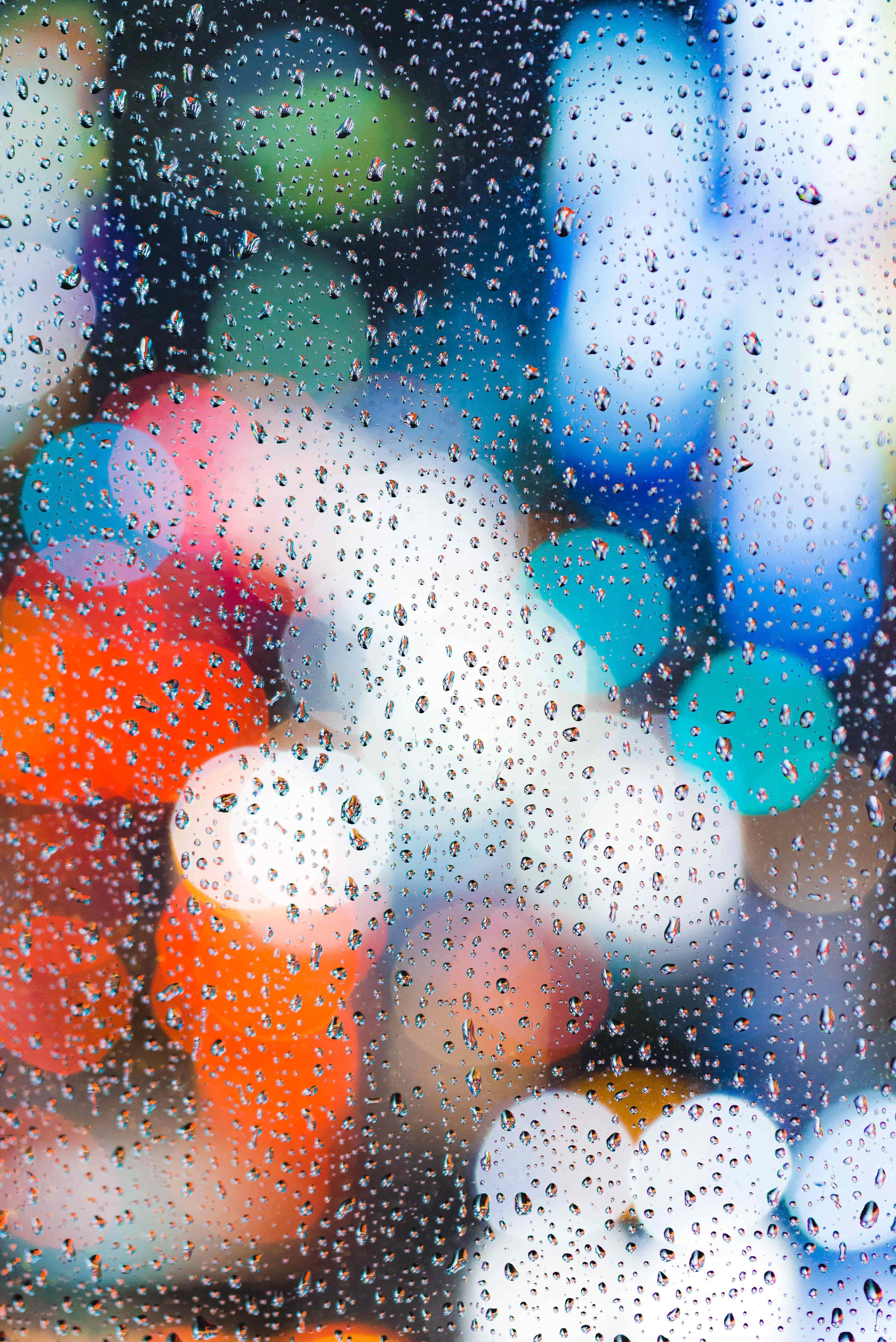 Water Drops 桌布 壁紙 — 雨滴依附在玻璃窗上，模糊的城市燈光在背後形成鮮豔的散景。