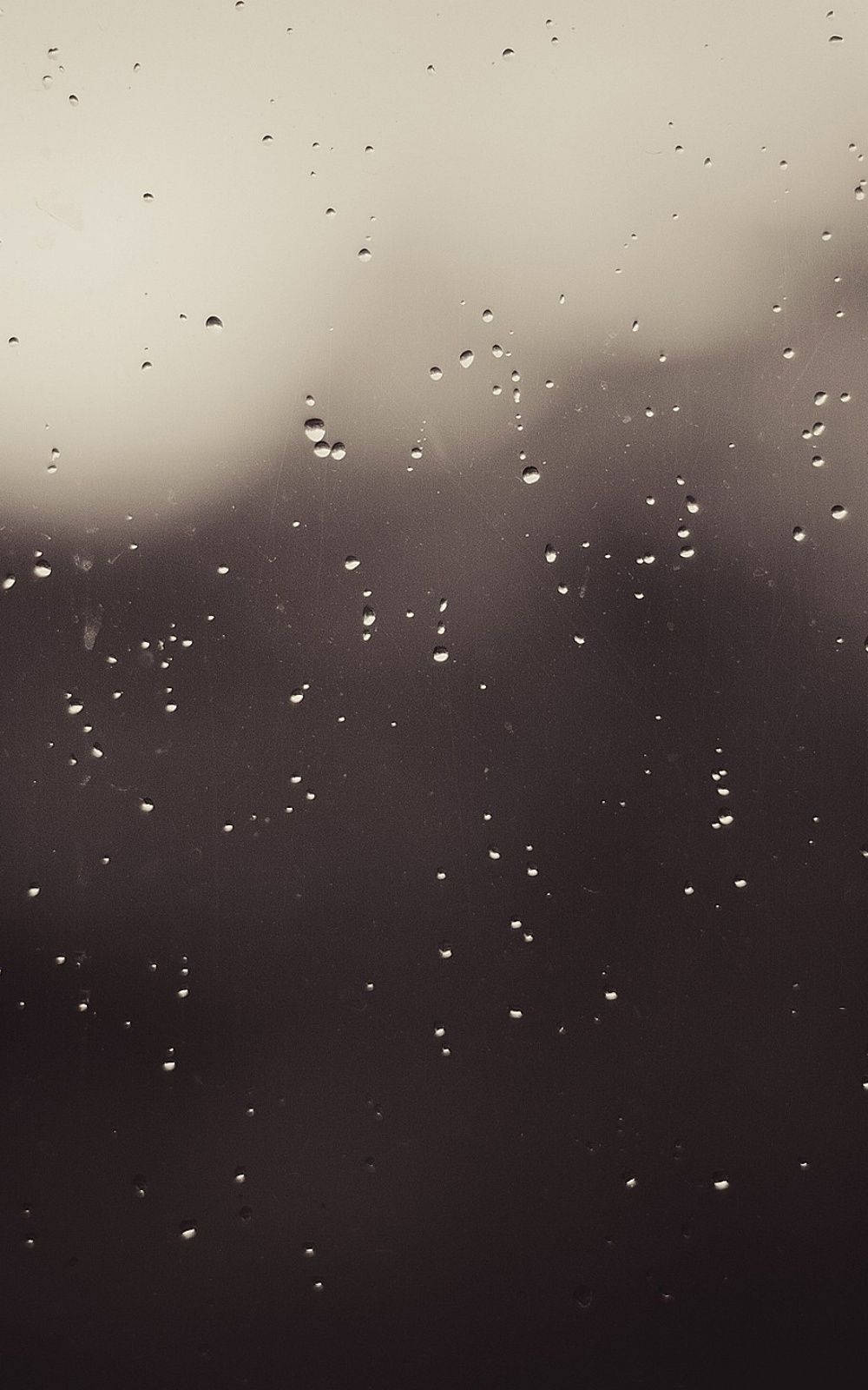 iPhone 桌布 壁紙 — 雨滴依附在玻璃窗上，陰沉天空透出柔和的灰色光線。
