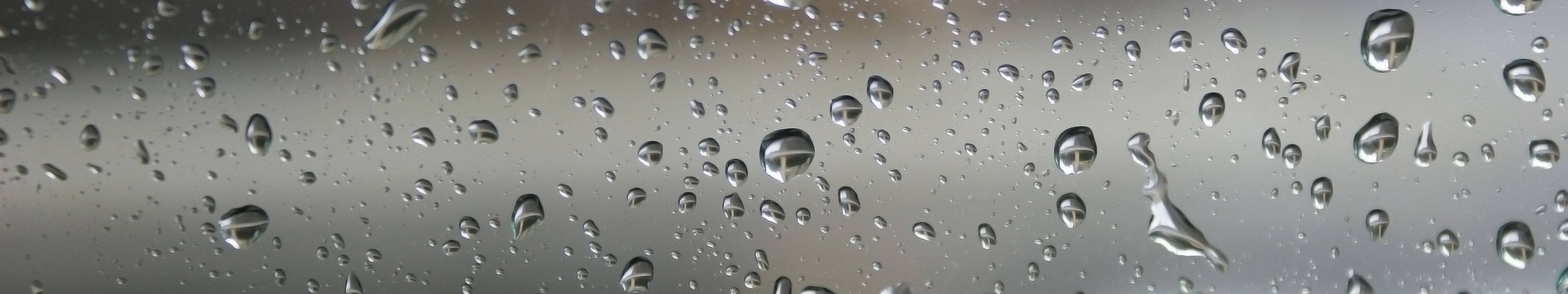 3 Monitor 桌布 壁紙 — 雨滴依附在玻璃表面，反射出柔和的灰色天空，特寫鏡頭。