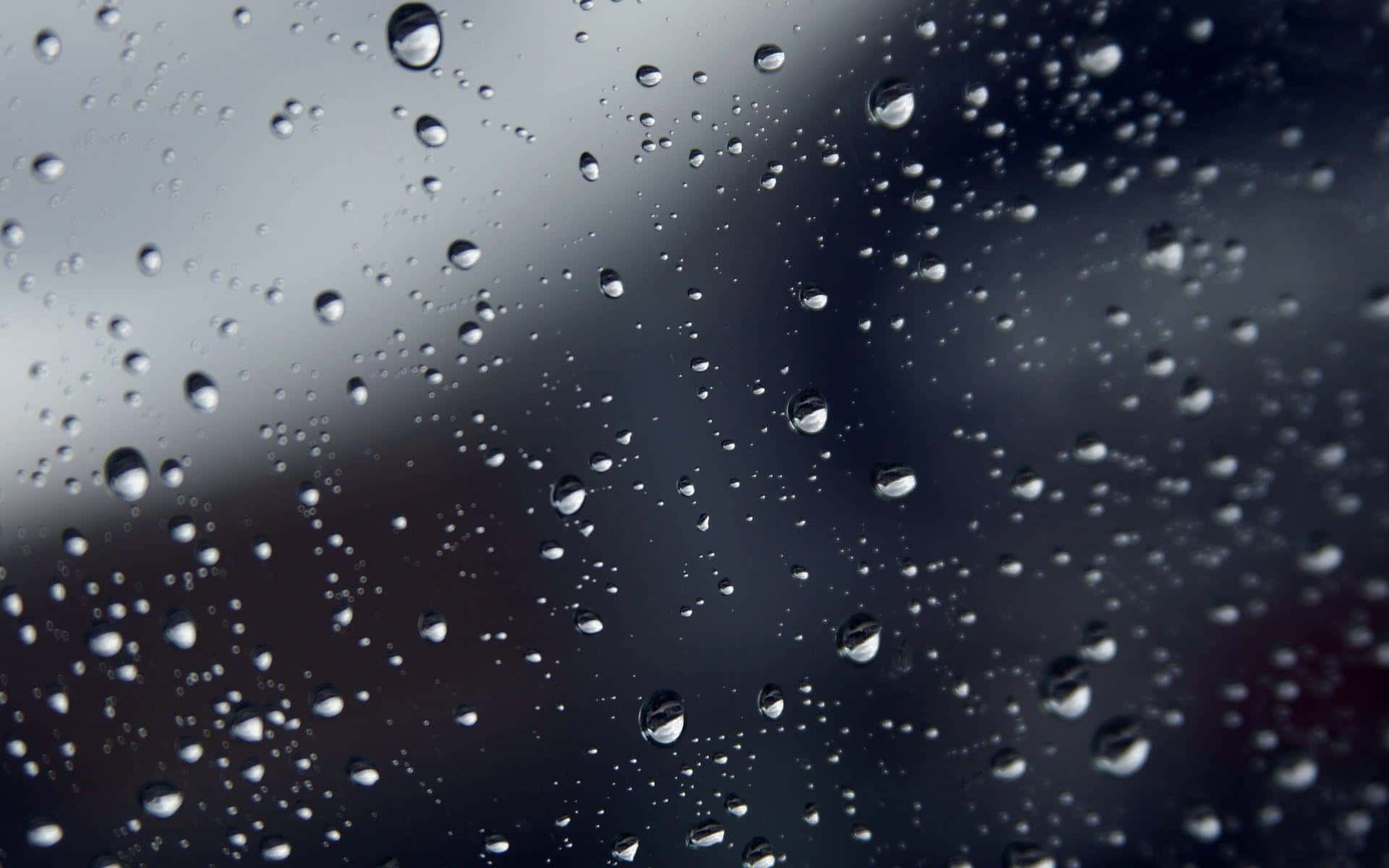 Rain Drops 桌布 壁紙 — 雨滴依附在玻璃表面，反射出陰沉的灰色天空和柔和模糊的背景。