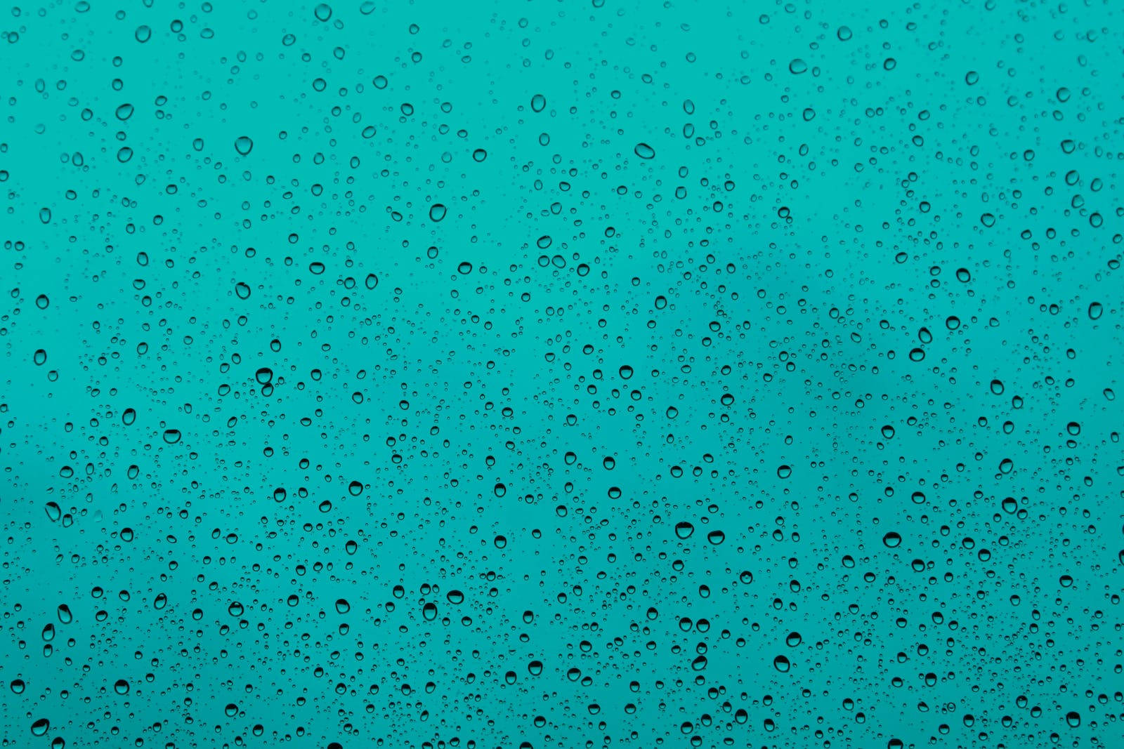 Raining 桌布 壁紙 — 雨滴依附在玻璃表面，露出背後充滿活力的青綠色天空。