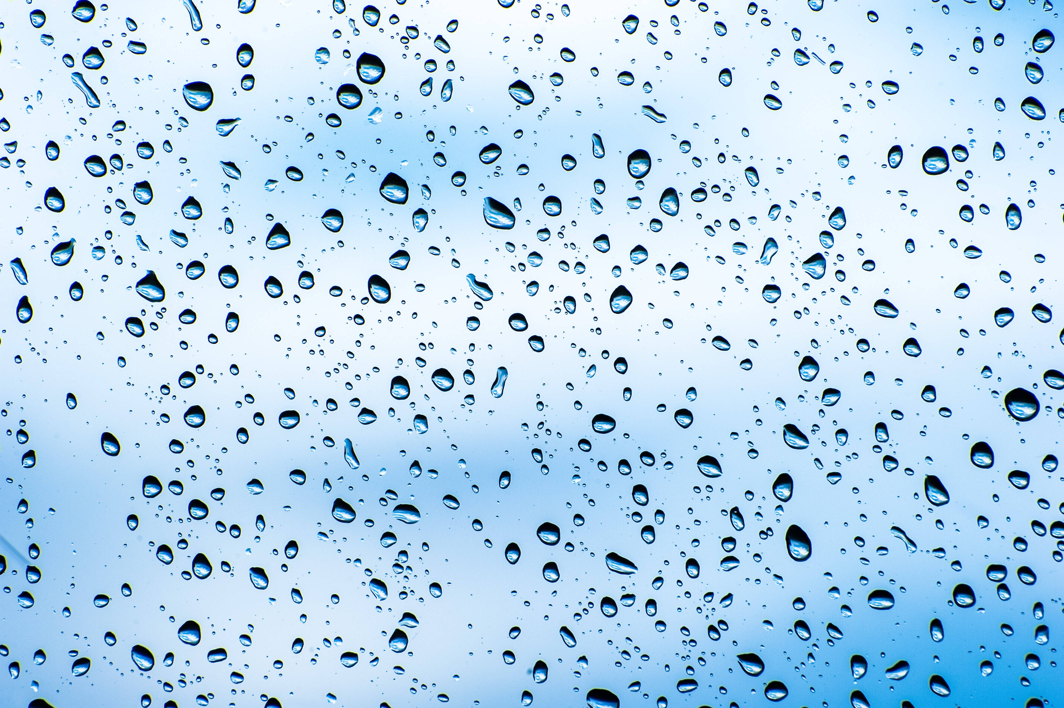 透明 桌布 壁紙 — 雨滴依附在玻璃表面，露出背後柔和的藍天。