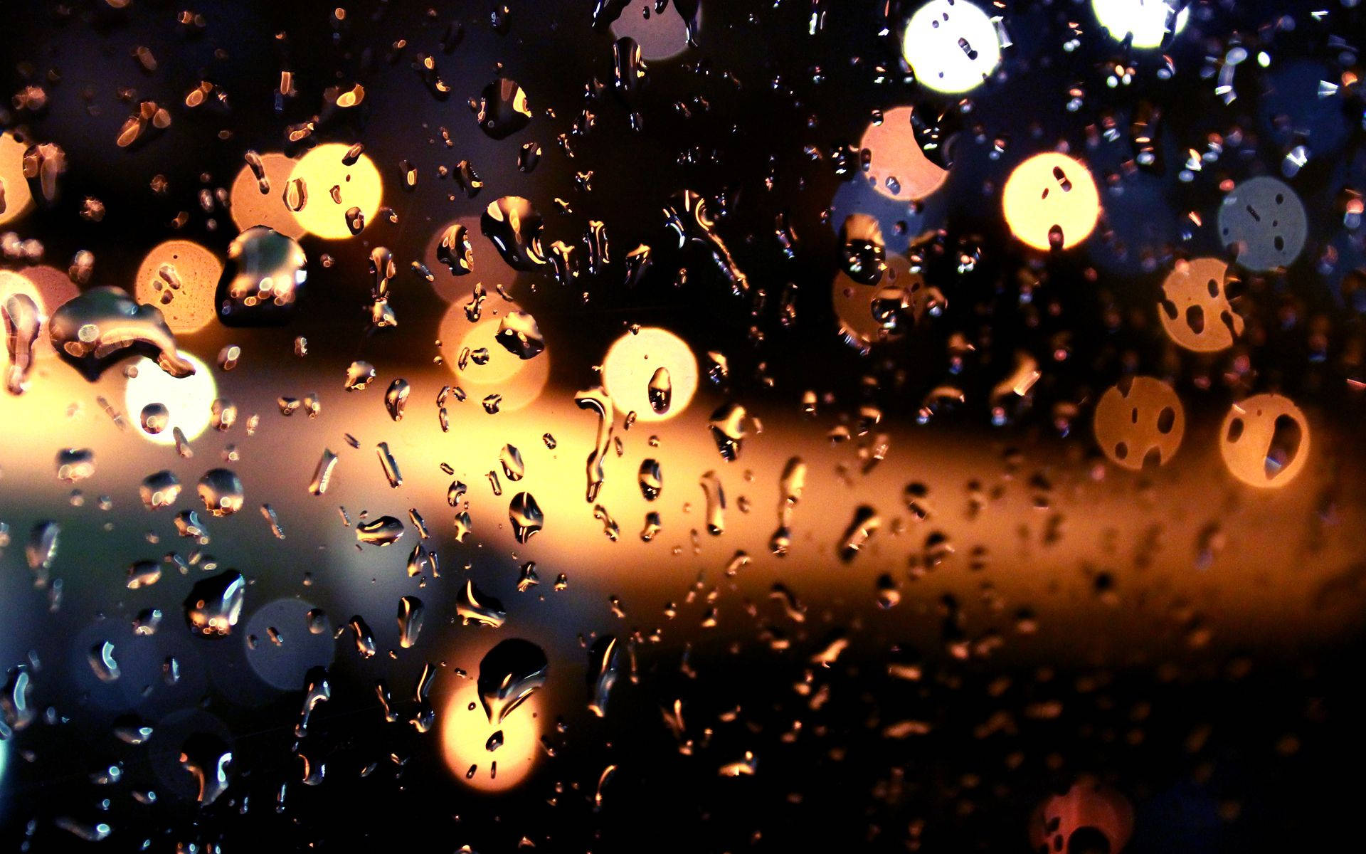 Rainy Day 桌布 壁紙 — 雨滴依附在窗戶上，扭曲了溫暖的金色散景燈光，映襯著黑暗的夜晚背景。
