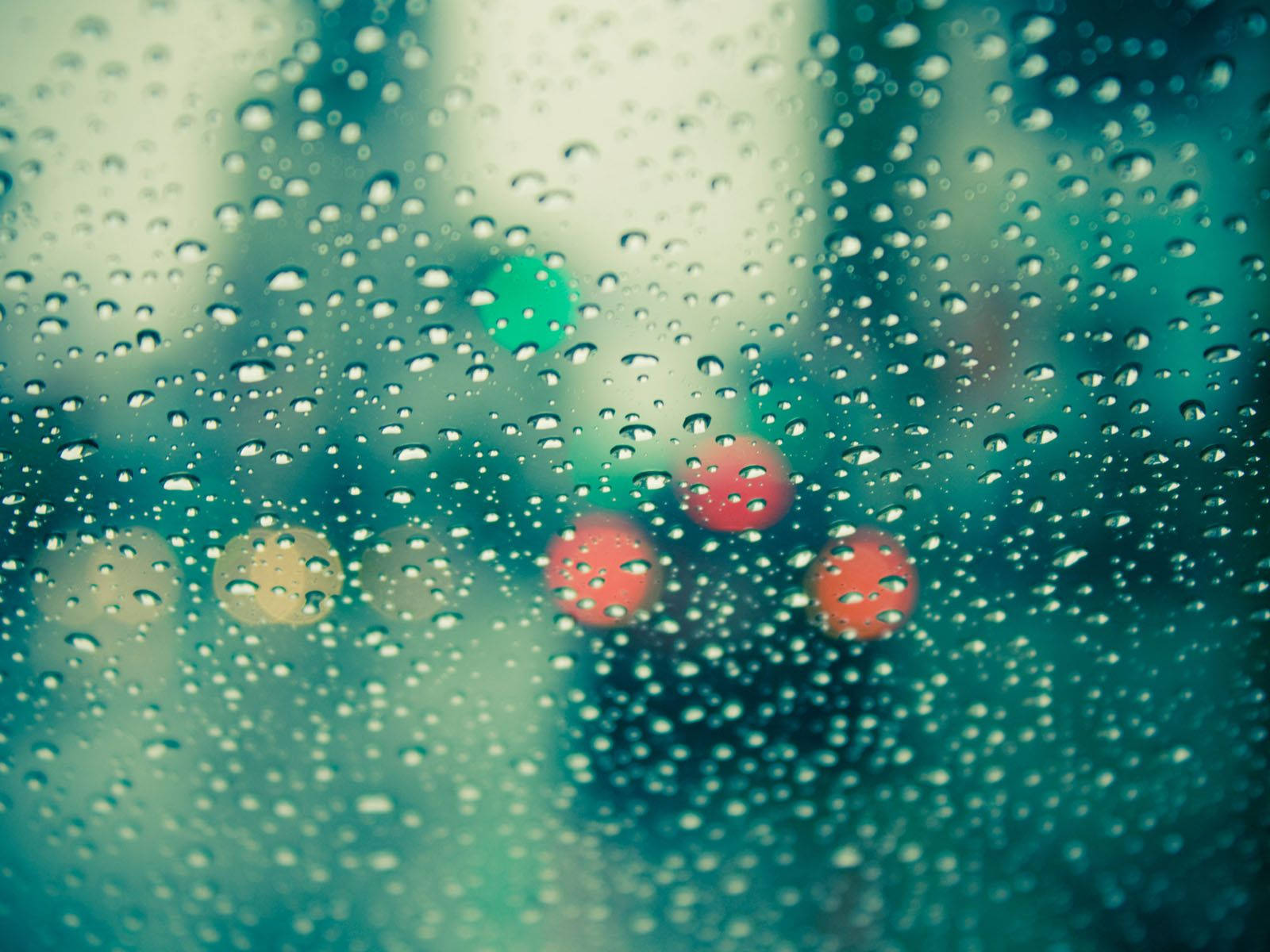 Rainy Day 桌布 壁紙 — 雨滴依附在窗戶上，顯露出模糊的城市燈光，呈現青綠色和紅色調。
