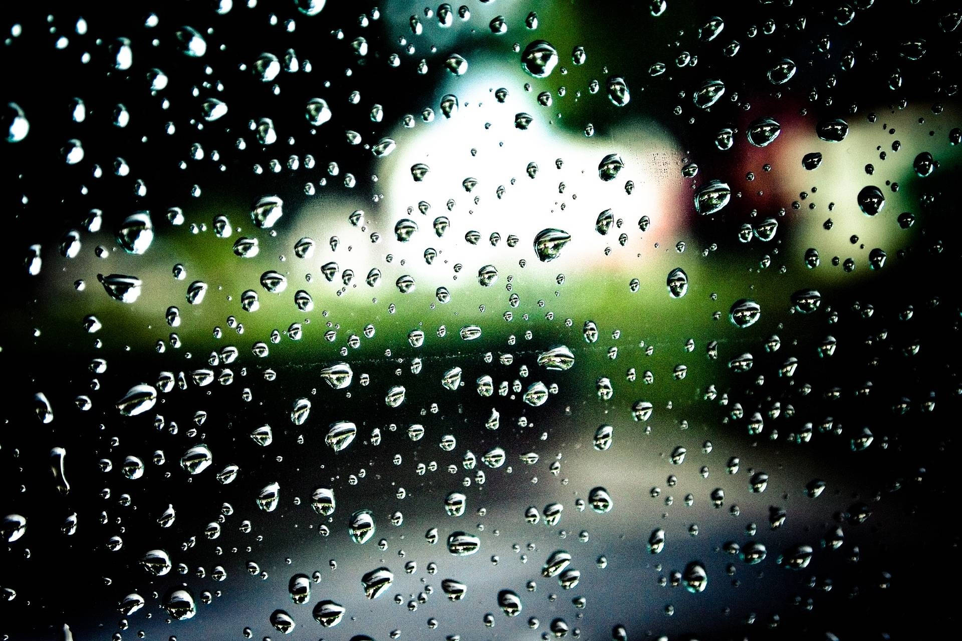 Rainy Day 桌布 壁紙 — 雨滴依附在窗戶上，顯露出模糊的綠色和白色戶外場景。