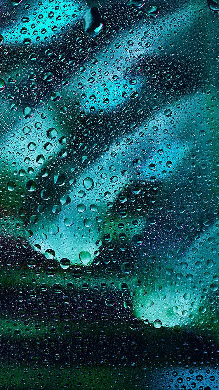 Raining 桌布 壁紙 — 雨滴依附在窗戶上，顯露出模糊的藍綠色和綠色天空，帶有柔和的雲朵。