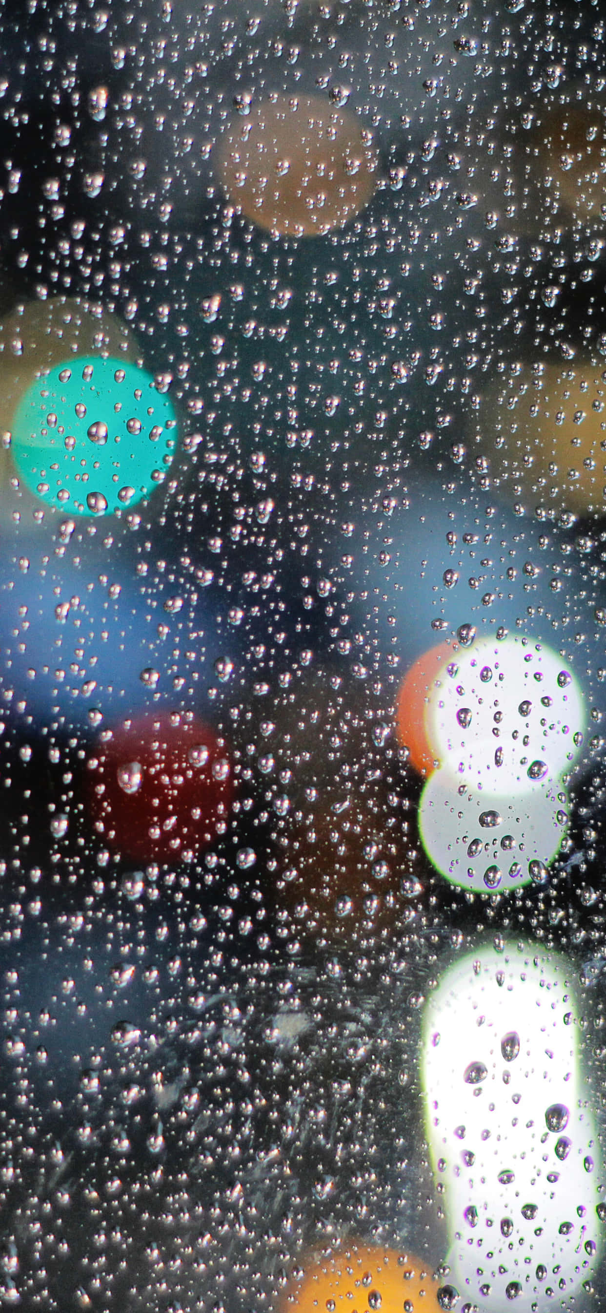 iPhone 桌布 壁紙 — 雨滴依附在窗戶上，顯露出溫暖與冷色調中模糊的城市燈光。