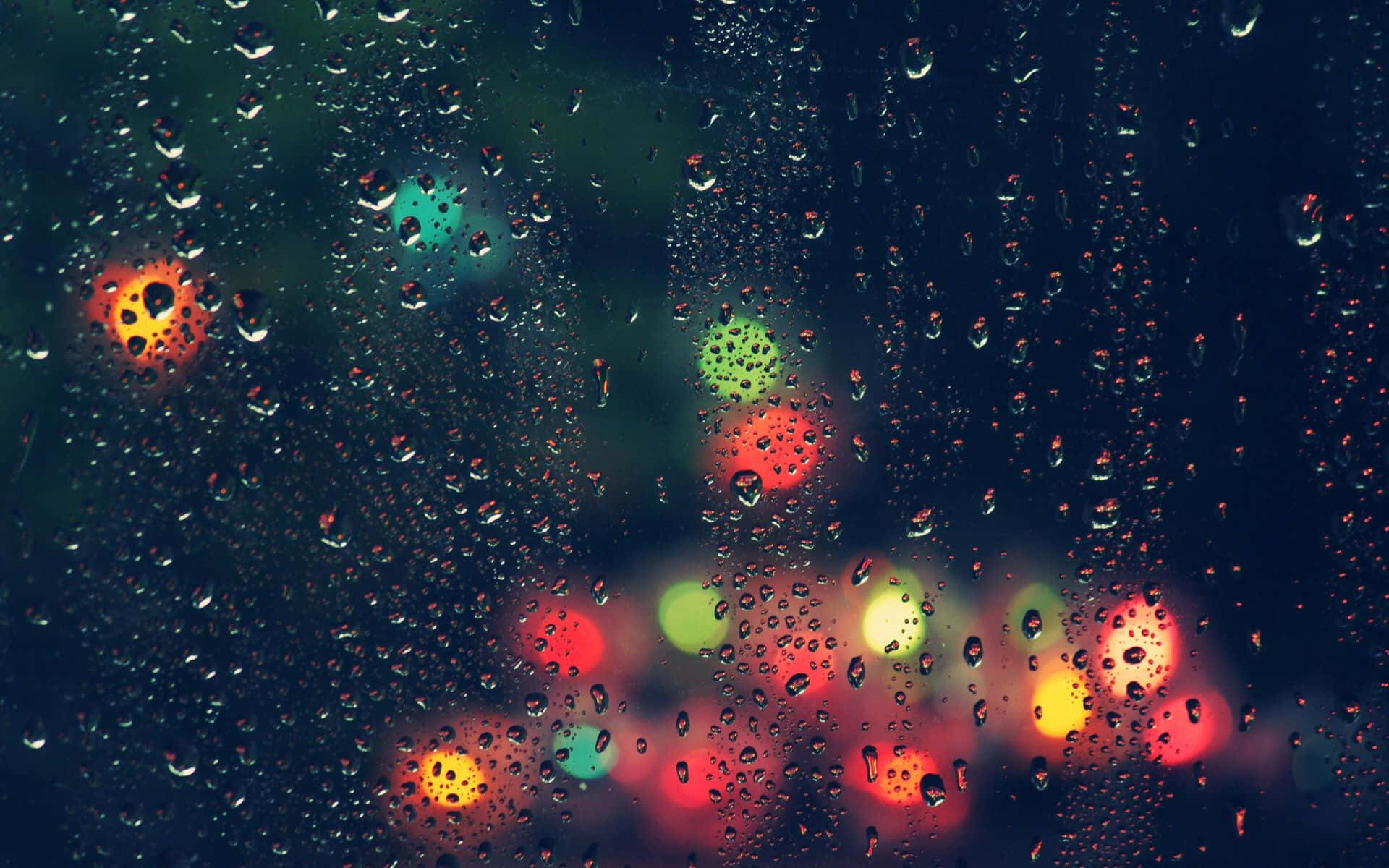 Rainy 桌布 壁紙 — 雨滴依附在窗戶上，顯露出漆黑夜晚中模糊多彩的城市燈光。