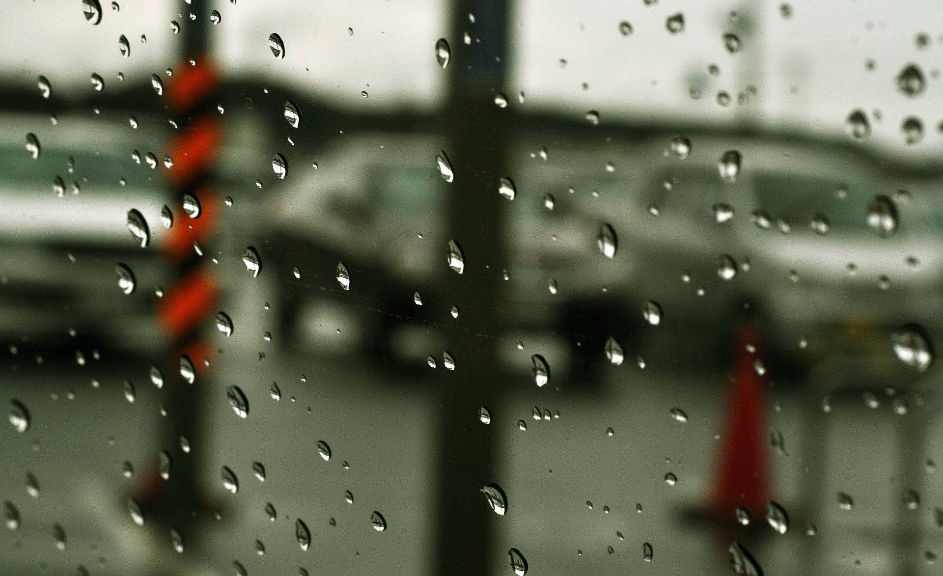 Rainy Day 桌布 壁紙 — 雨滴依附在窗玻璃上，模糊了灰色的城市街道，有汽車和橙色交通錐。