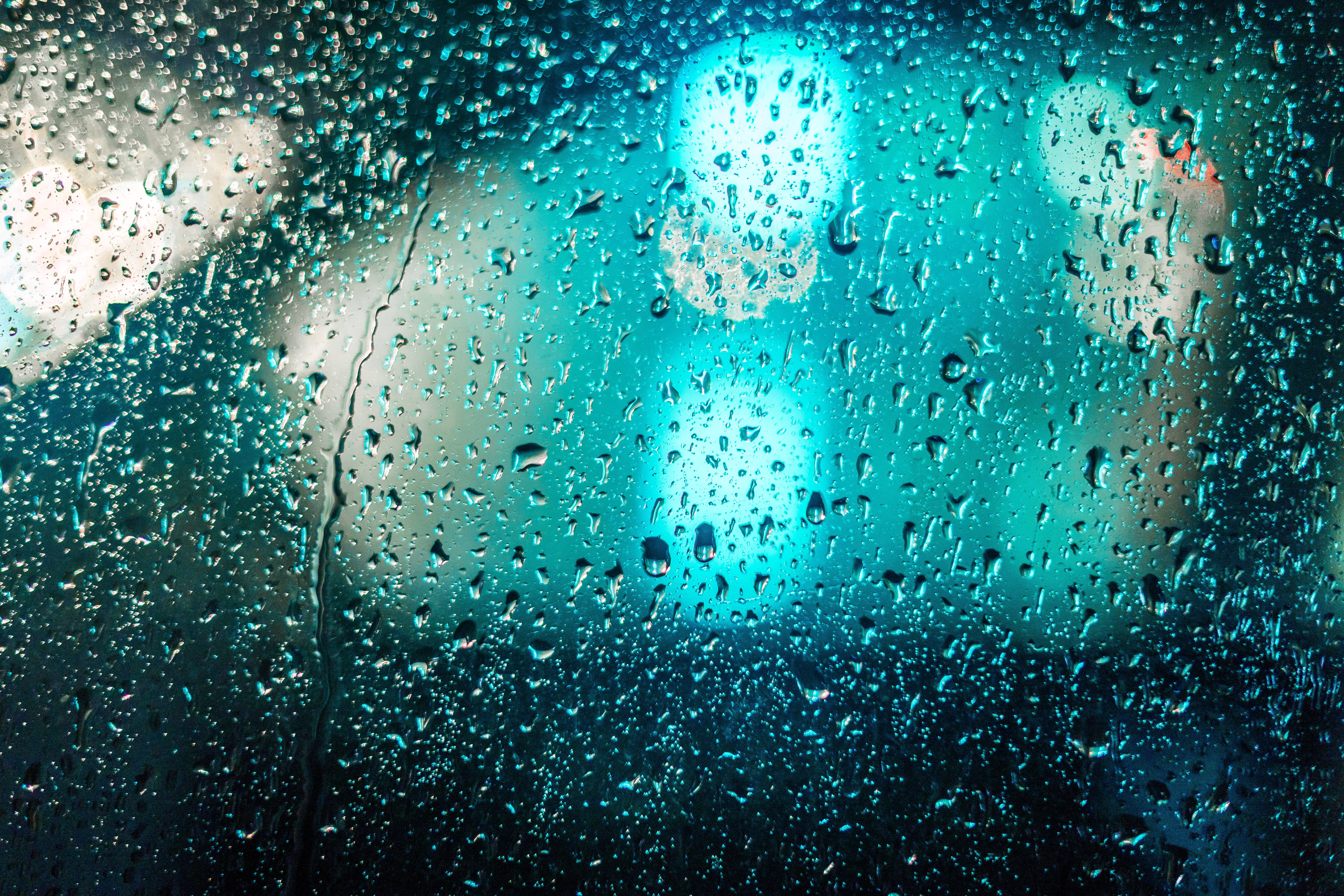 Raindrops 桌布 壁紙 — 雨滴劃過窗戶，顯露出夜晚模糊的藍綠色城市燈光。