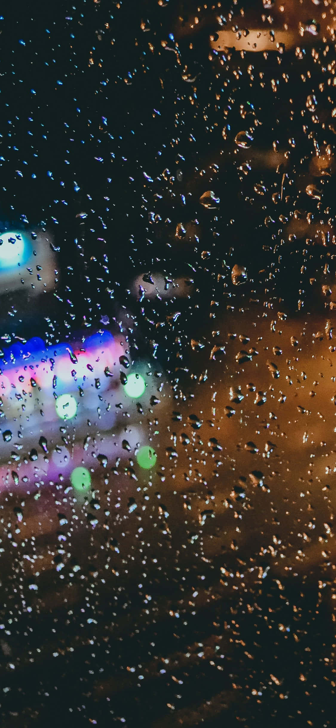 iPhone X 桌布 壁紙 — 雨滴劃過窗戶，顯露出模糊的城市燈光，在夜晚散發出溫暖與冷色調的光芒。
