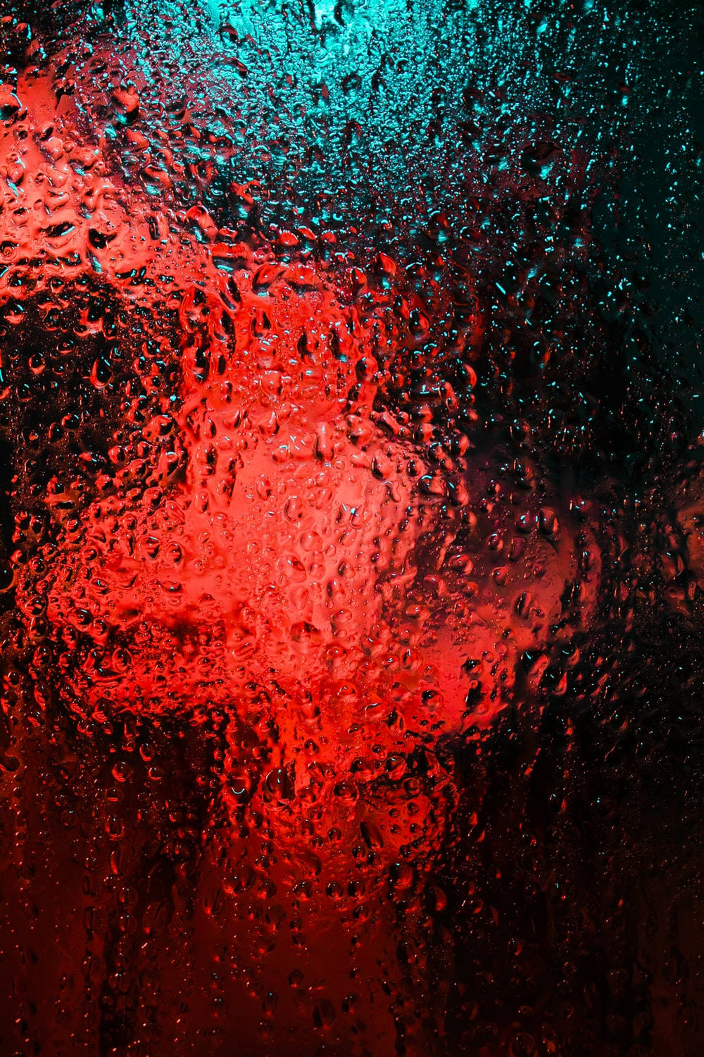 Red And Blue 桌布 壁紙 — 雨滴劃過窗戶，顯露出窗外充滿活力的紅色和藍綠色照明場景。