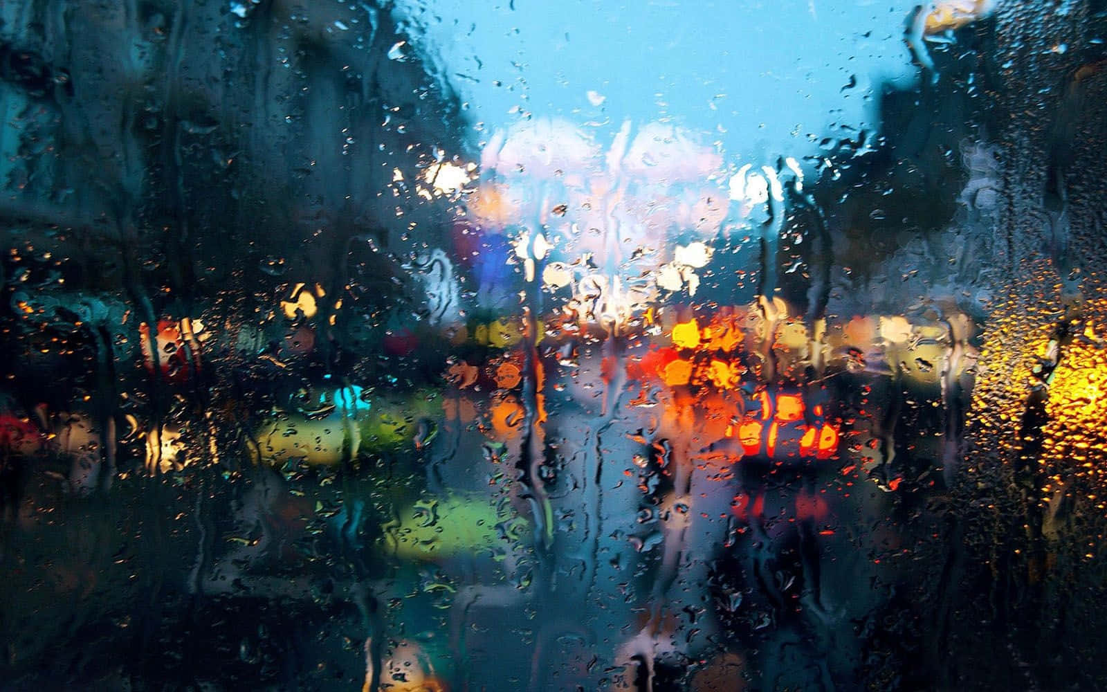 Raining 桌布 壁紙 — 雨滴劃過車窗，將充滿活力的城市燈光模糊成發光的抽象條紋，映襯著涼爽的藍色暮色。