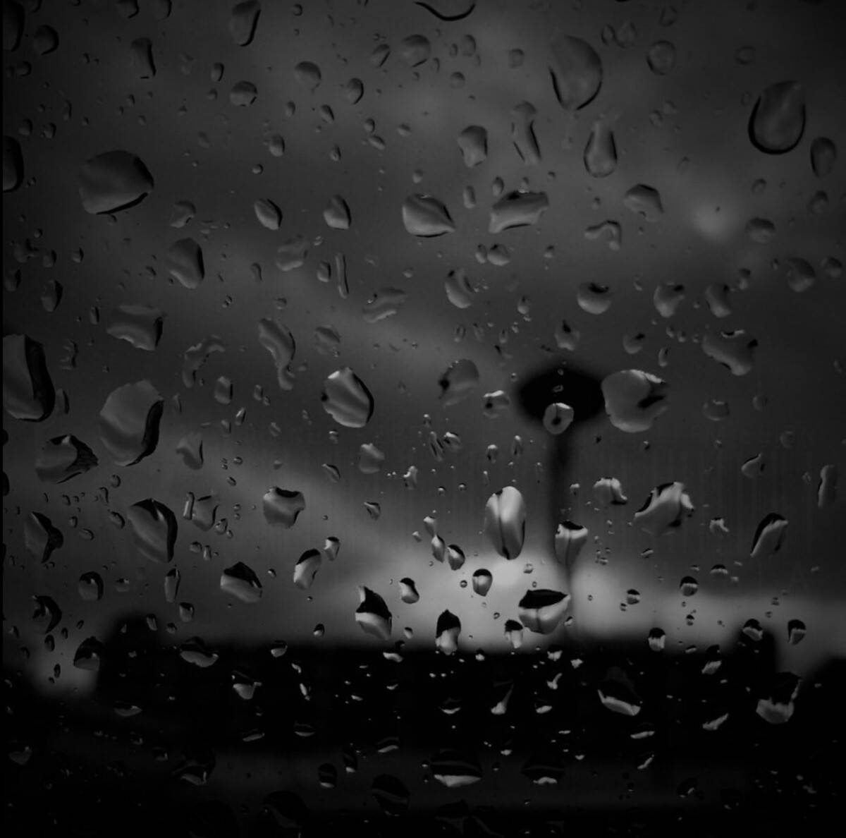 Rainy Day 桌布 壁紙 — 雨滴劃過車窗，模糊了遠處塔樓在陰沉灰色天空下的黑暗輪廓。