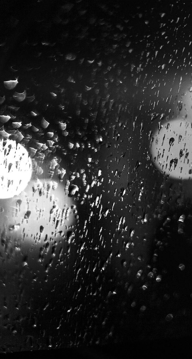 桌布 壁紙 — 雨滴劃過黑暗的窗戶，將閃爍的城市燈光模糊成柔和的圓形散景。