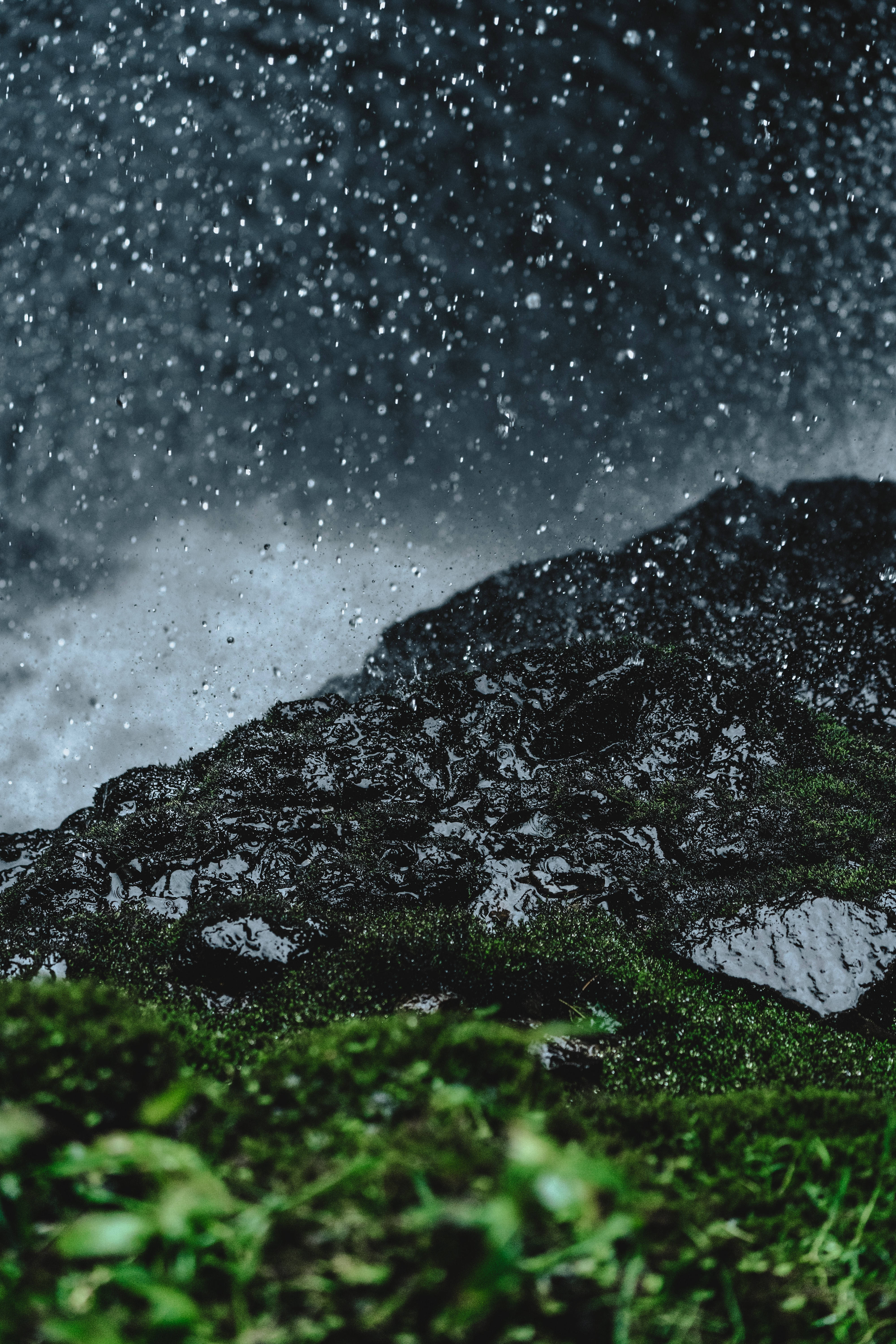 下雨 桌布 壁紙 — 雨滴在暴風雨的灰色天空下戲劇性地傾瀉在長滿苔蘚的岩石表面。