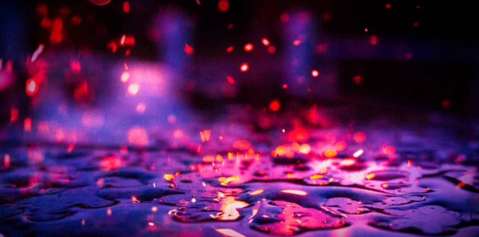 暗色 桌布 壁紙 — 雨滴在潮濕的表面上閃閃發光，霓虹燈投射出充滿活力的紫色和粉紅色散景反射。