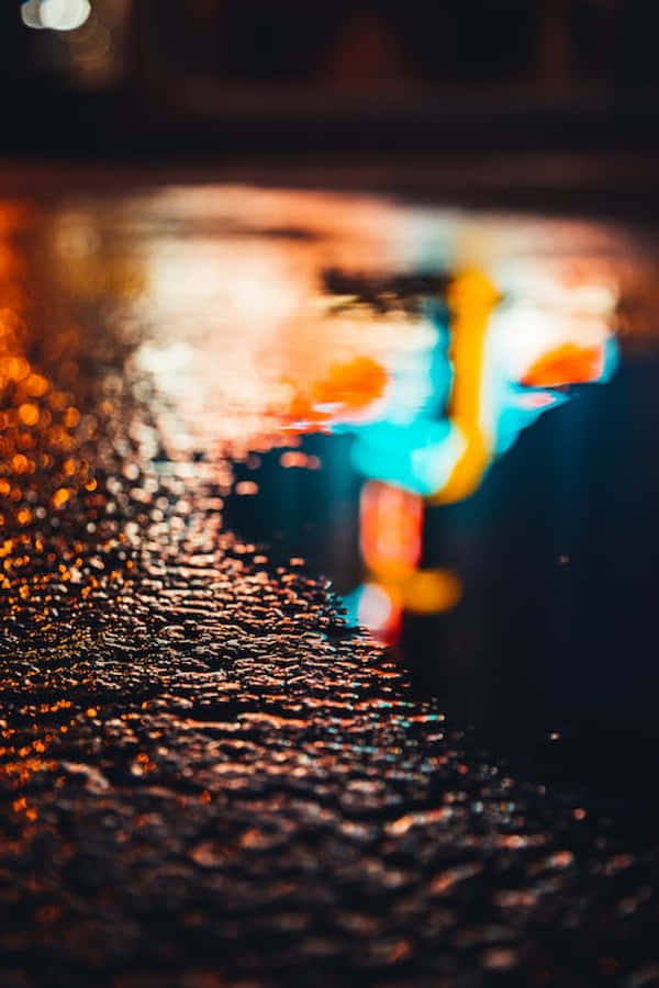 桌布 壁紙 — 雨滴在濕漉漉的人行道上閃閃發光，反射出夜間城市場景中模糊的霓虹燈光。