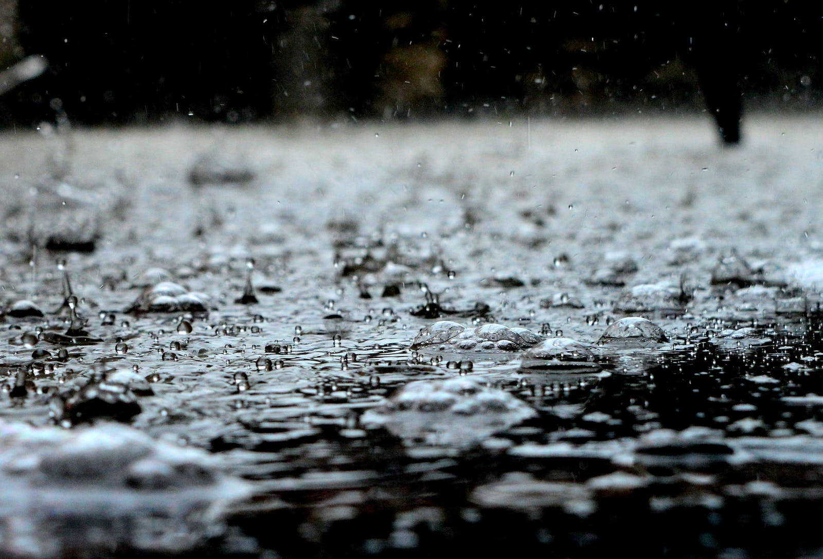 Raining 桌布 壁紙 — 雨滴在濕漉漉的路面上飛濺並泛起漣漪，營造出陰鬱的特寫鏡頭。