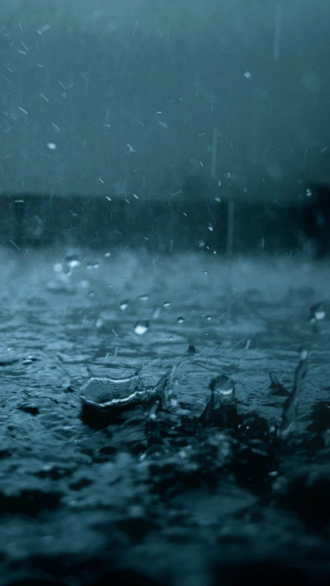 桌布 壁紙 — 雨滴在陰暗的天空和模糊的背景襯托下，戲劇性地濺落在黑暗的水面上。