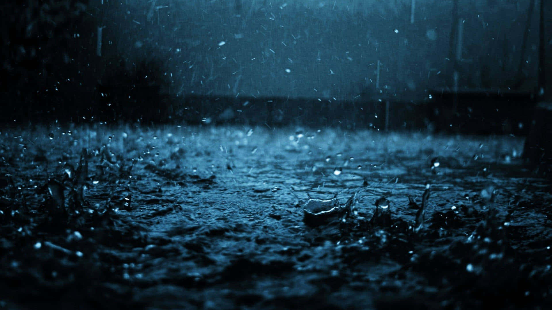 Rain 4K 桌布 壁紙 — 雨滴在黑暗潮濕的人行道上戲劇性地飛濺，背景是憂鬱的藍色夜空。