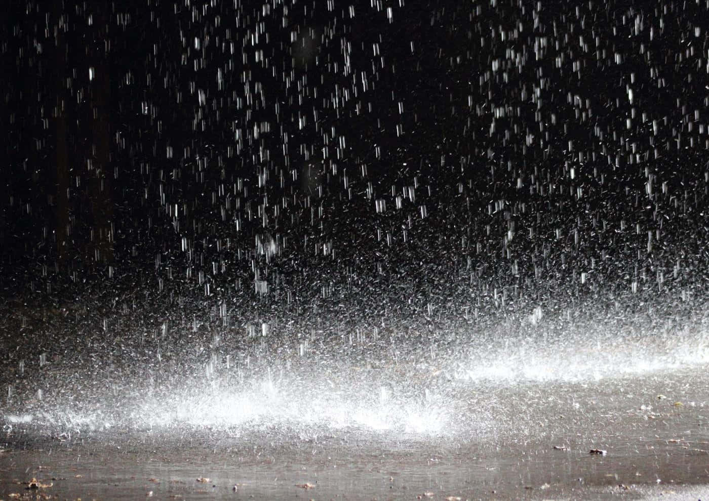 下雨 桌布 壁紙 — 雨滴在黑暗背景下傾瀉而下，明亮的白色水花擊中下方的潮濕表面。