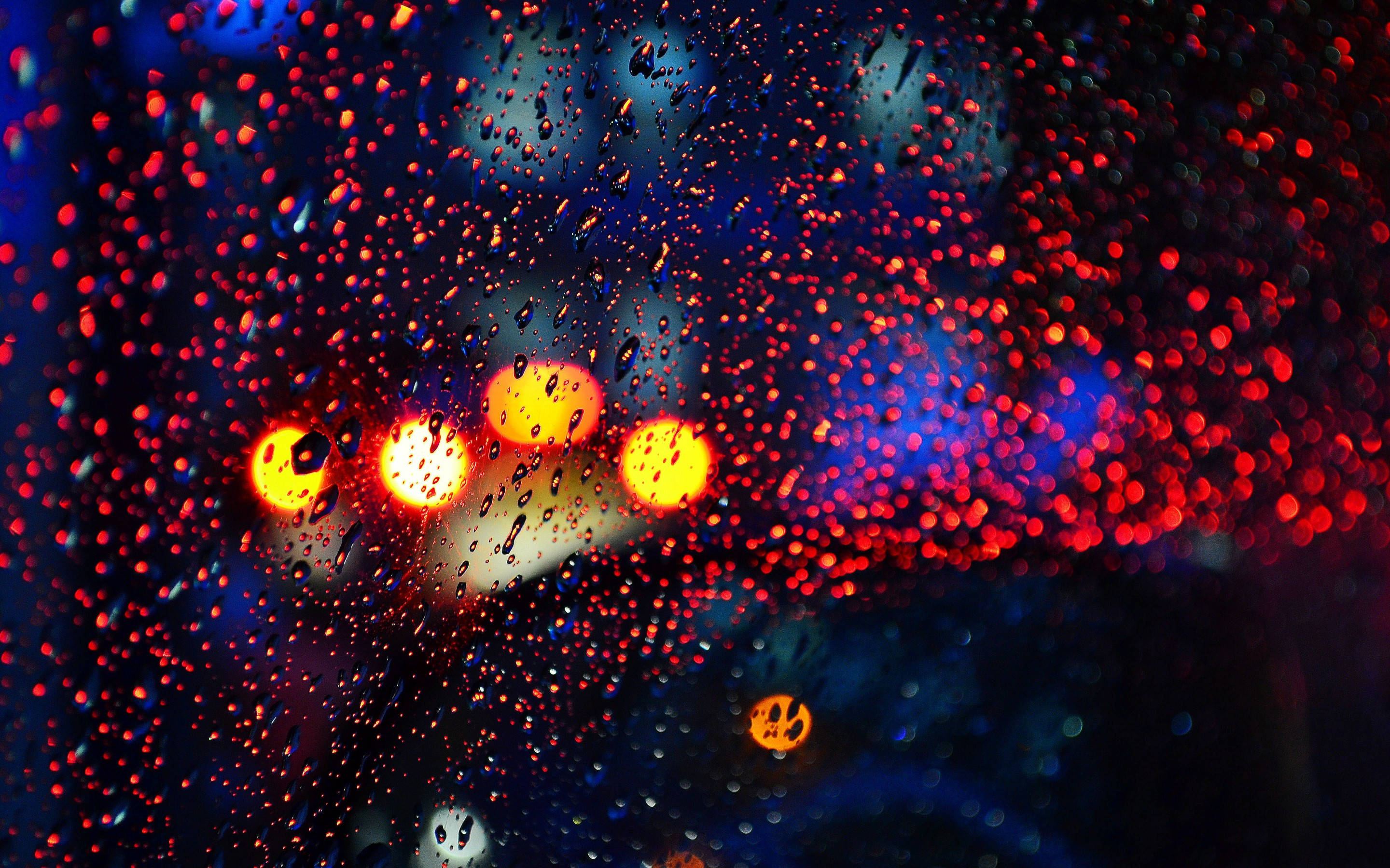 紅色與藍色 桌布 壁紙 — 雨滴將夜間濕窗上鮮豔的紅色和藍色城市燈光模糊成發光球體。