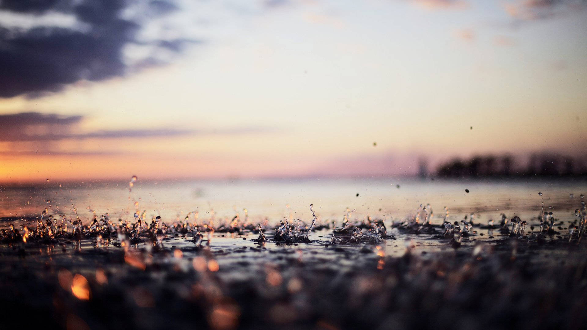 natural 桌布 壁紙 — 雨滴戲劇性地濺在濕地上，柔和的夕陽在水天模糊的地平線上以溫暖色調塗抹天空。