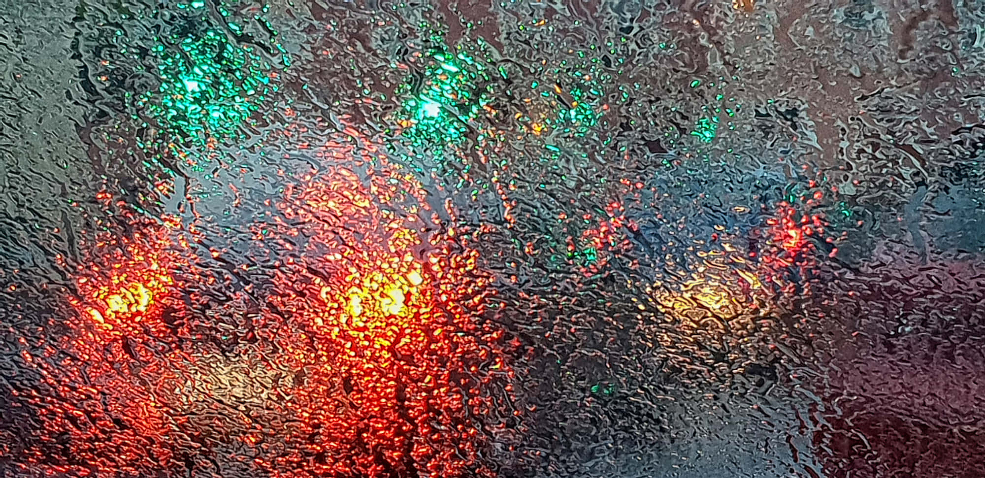 glass 桌布 壁紙 — 雨滴扭曲了濕窗上鮮豔的紅色和綠色燈光，營造出陰鬱的抽象光芒。