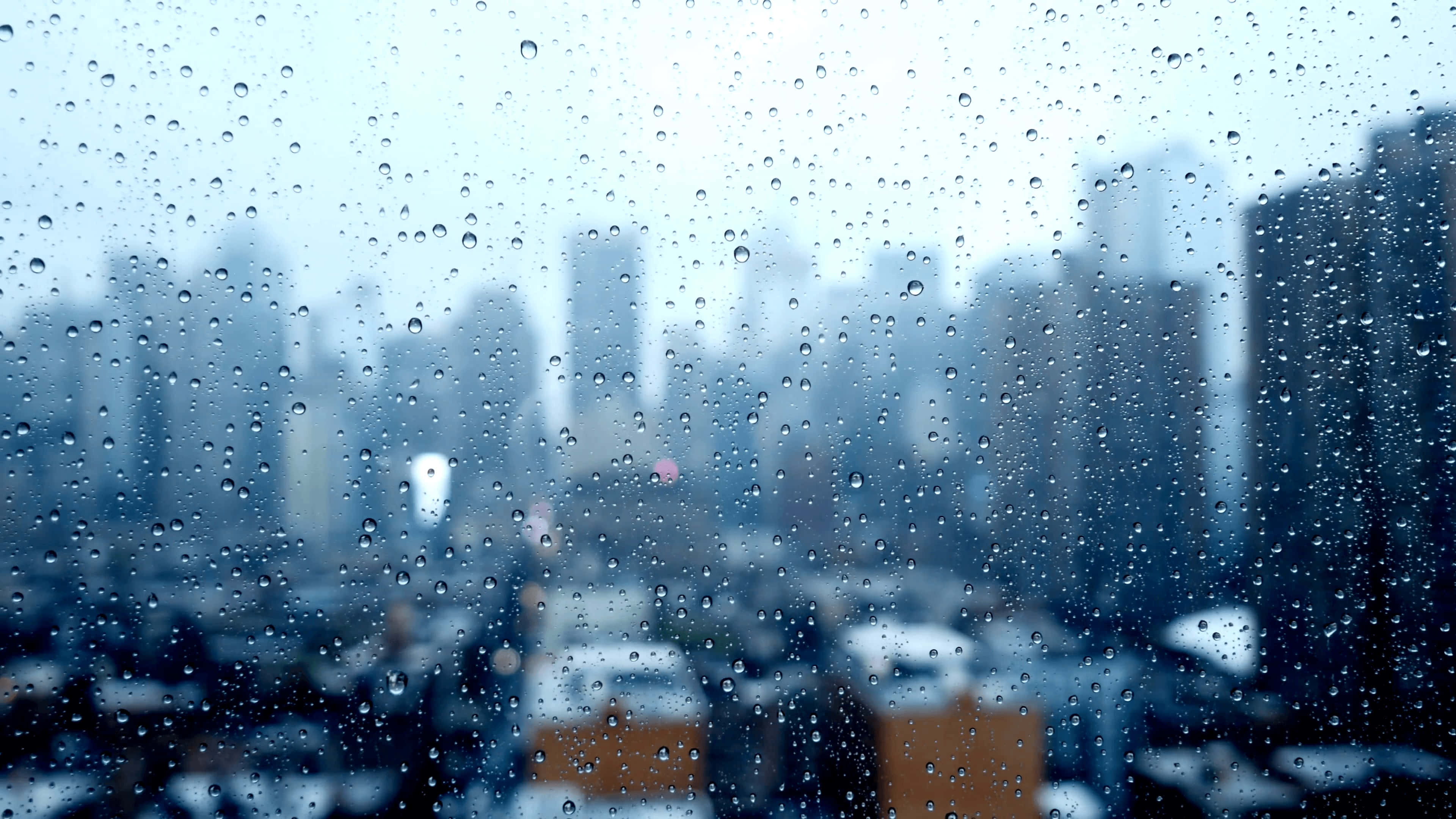 下雨 桌布 壁紙 — 雨滴模糊了從窗戶看到的陰暗日子裡朦朧的城市景觀。